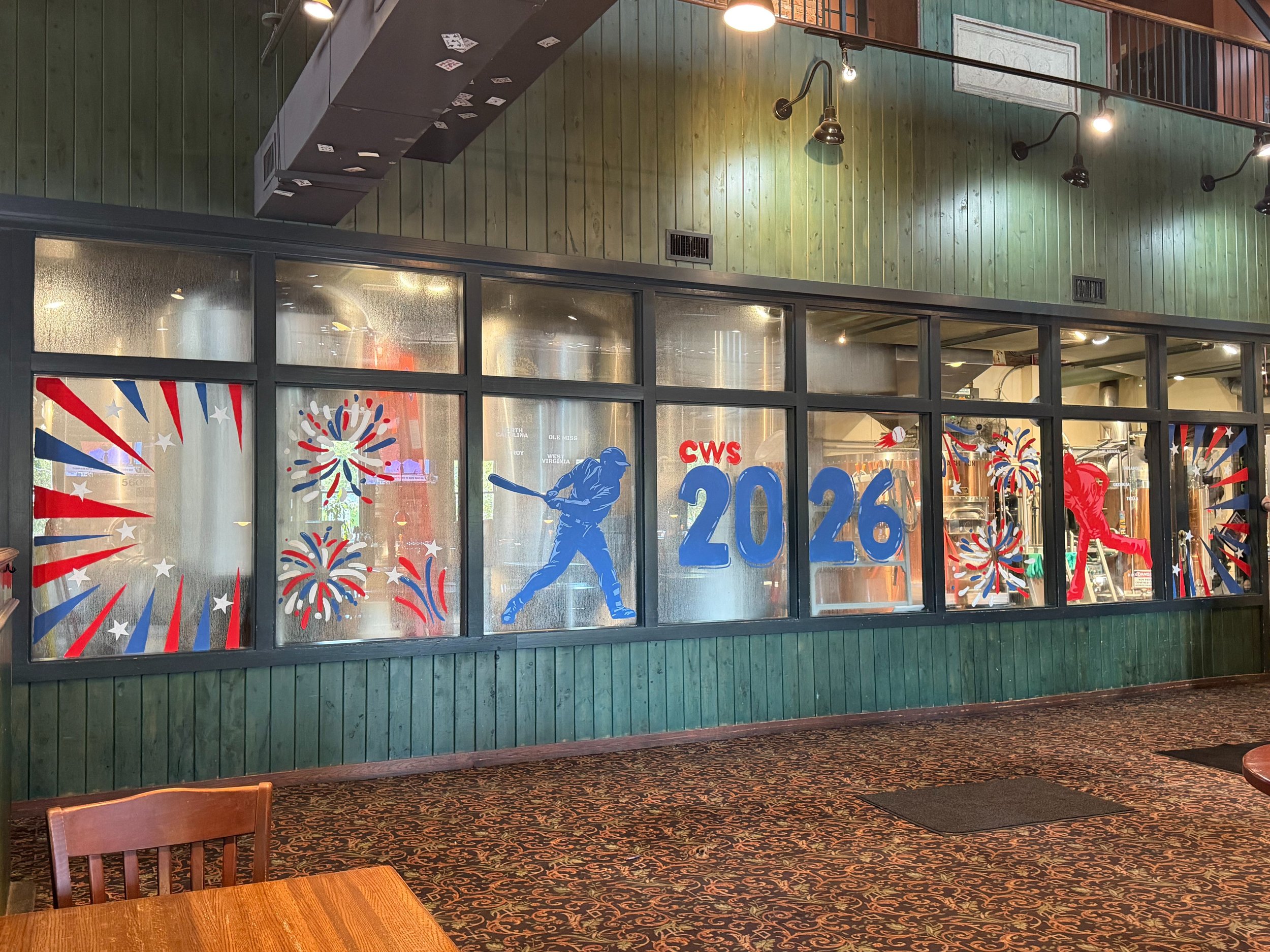 window mural that is in red white and blue with baseball players, stars, fireworks, stripes and says cws 2026.