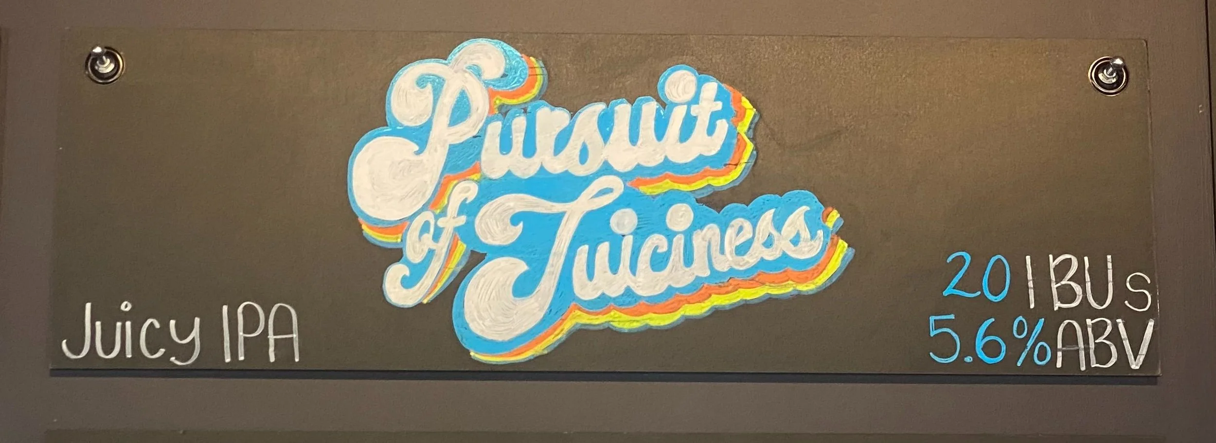 70s funky inspired chalk design that says Pursuit of Juciness in white, blue, orange, and yellow. Says juicy IPA at the bottom right.