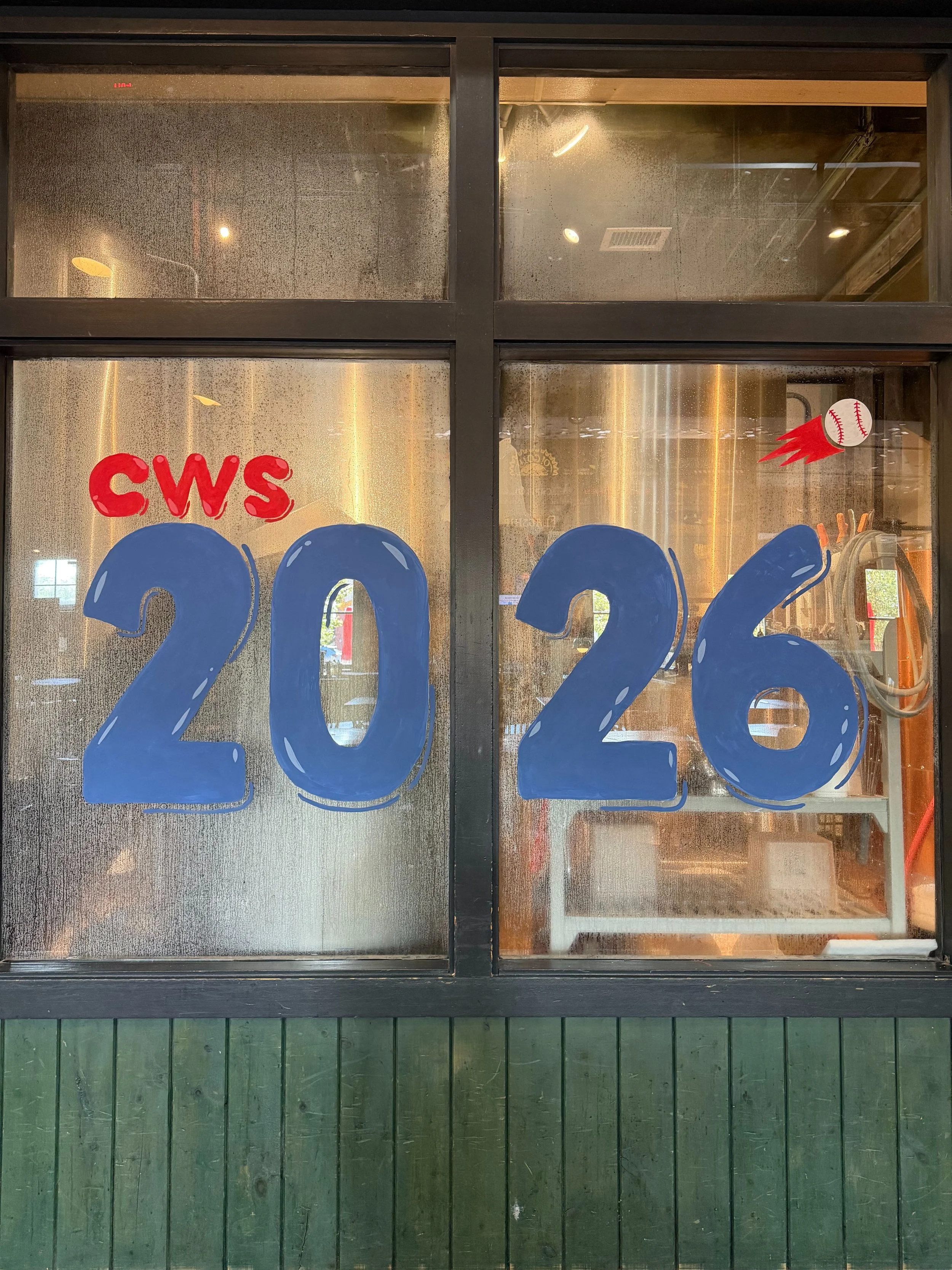 painted window that says cws in red and 2026 in blue with a painted baseball flying above