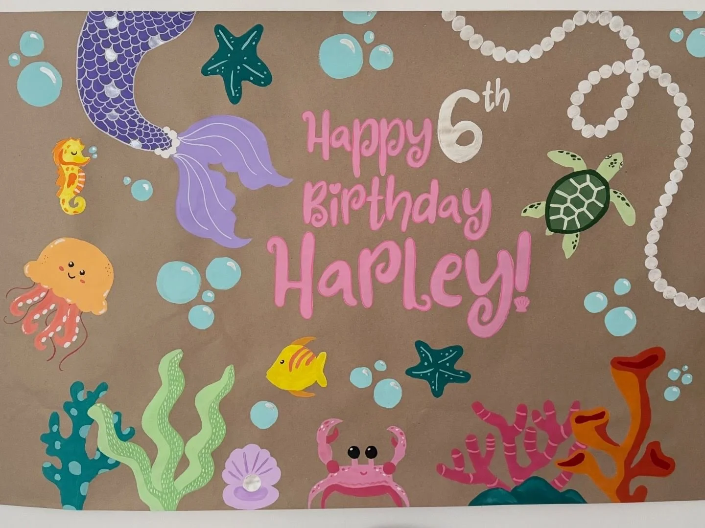banner art that says happy 6th birthday harley. sea animals like fish, a crab, turtle, jellyfish and a mermaid are on it. with a string of pearls and bubbles and sea coral on the bottom and a pearl in a shell.