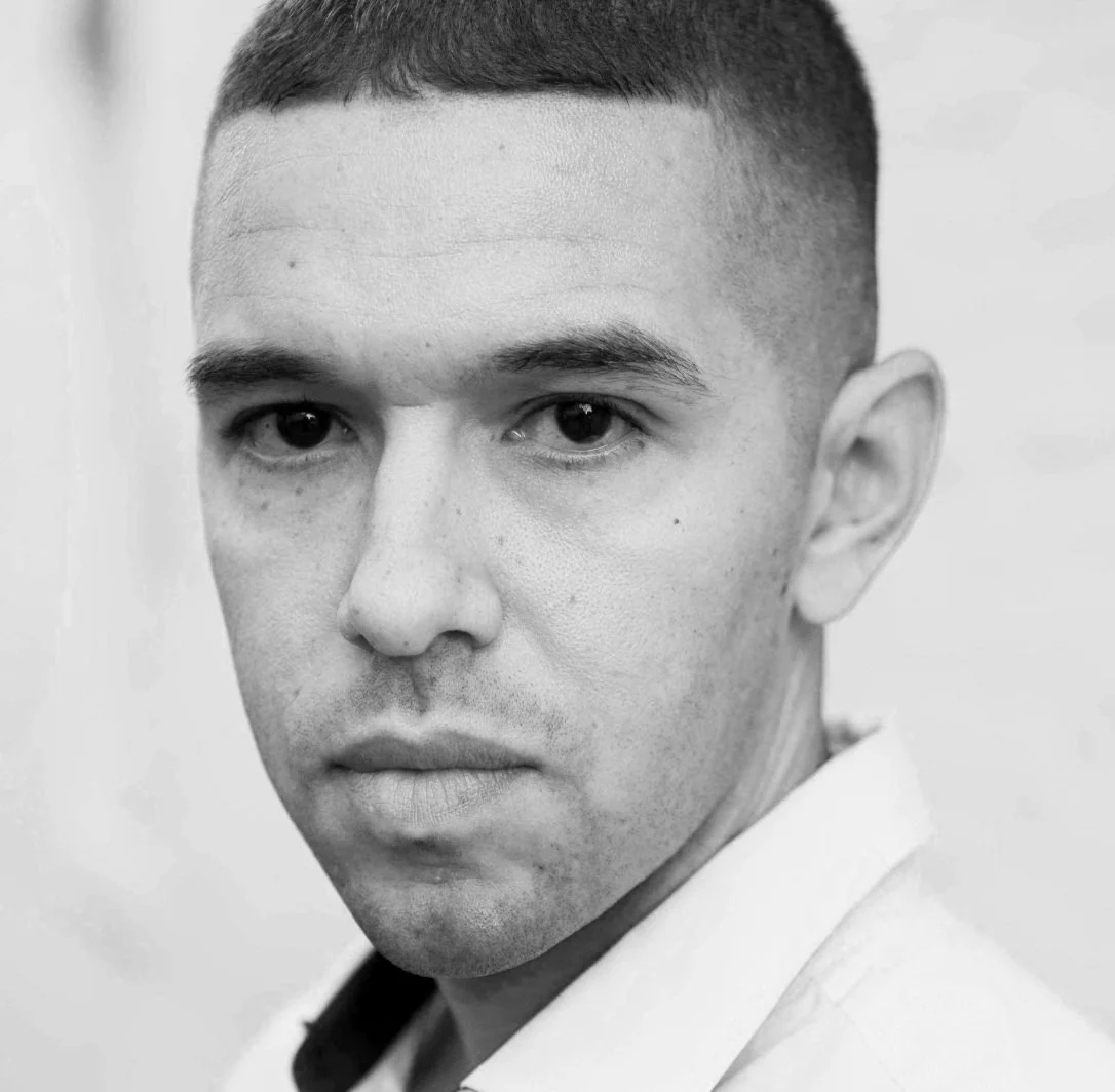 Close-up black and white photo of a young man with short hair, wearing a collared shirt.