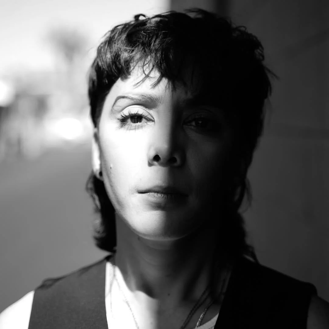 Black and white portrait of a woman with short hair, half of her face illuminated by light and the other half in shadow.