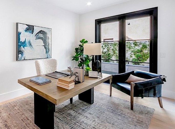 Luxury Modern home staging with a wooden desk, black leather chair, abstract artwork, faux plant in Huntington Beach, California