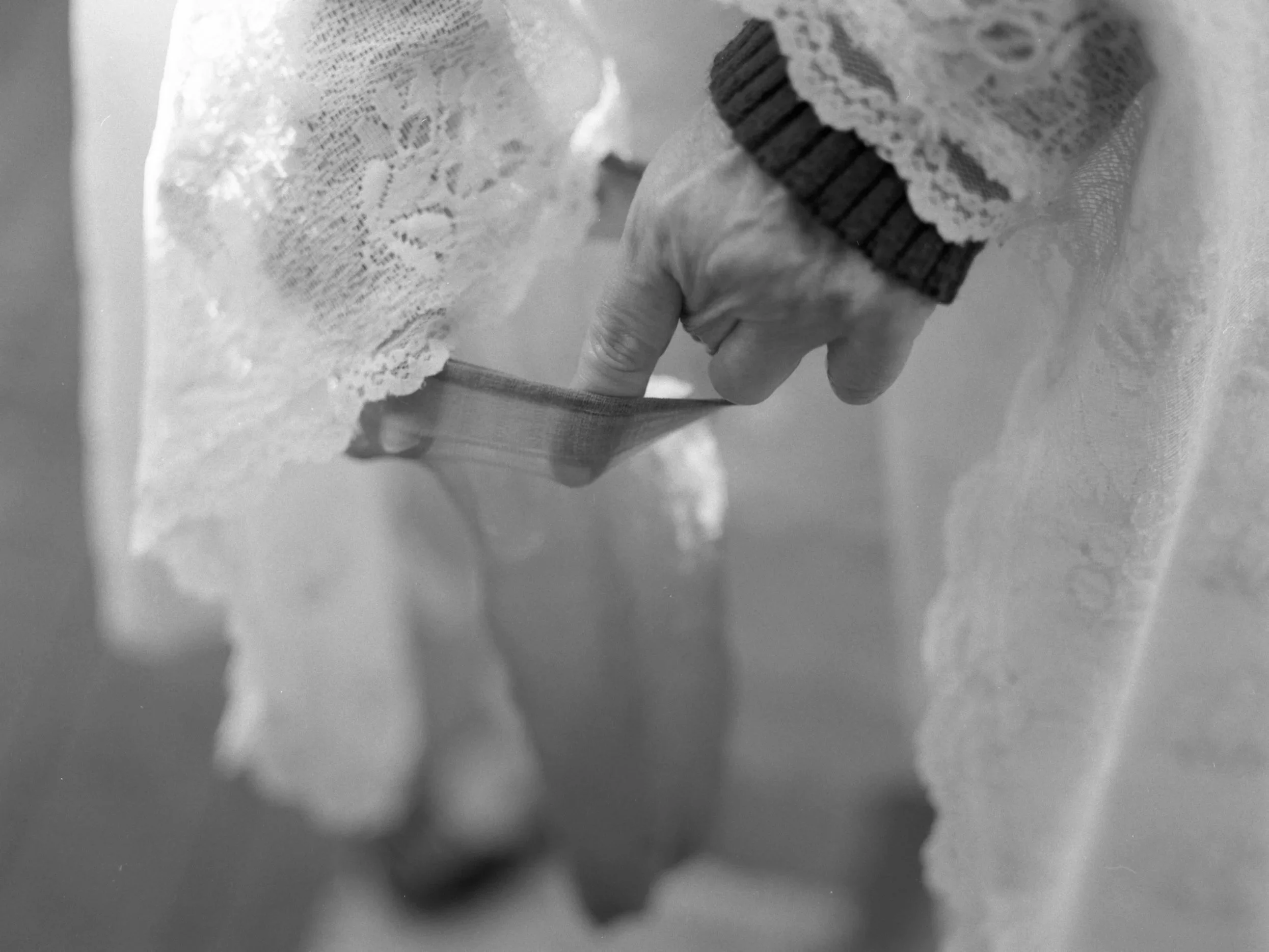 Close-up of a hand with a lace sleeve, holding a paintbrush and painting a surface.