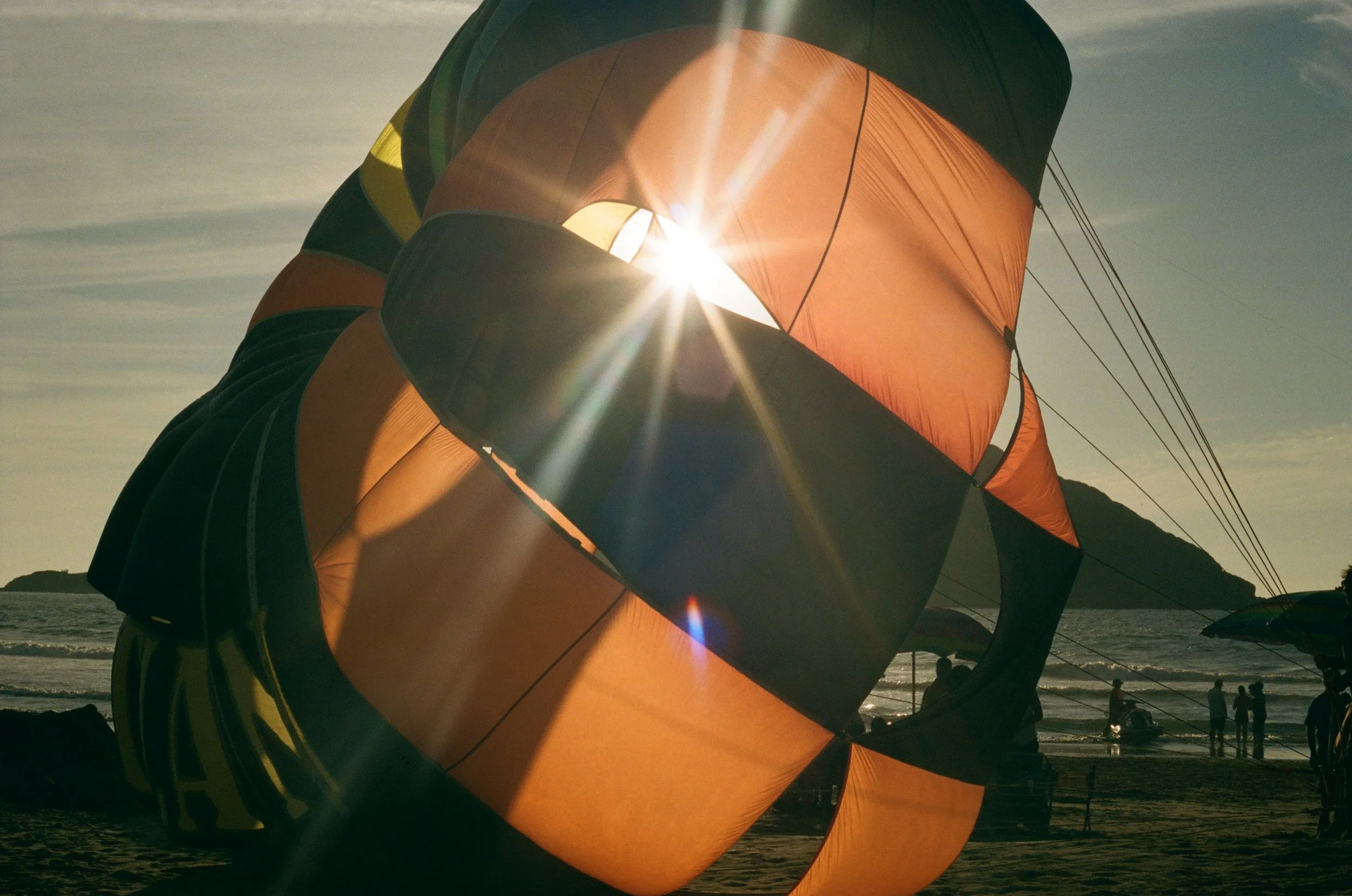 Colorful hot air balloons on the beach with the sunset in the background.