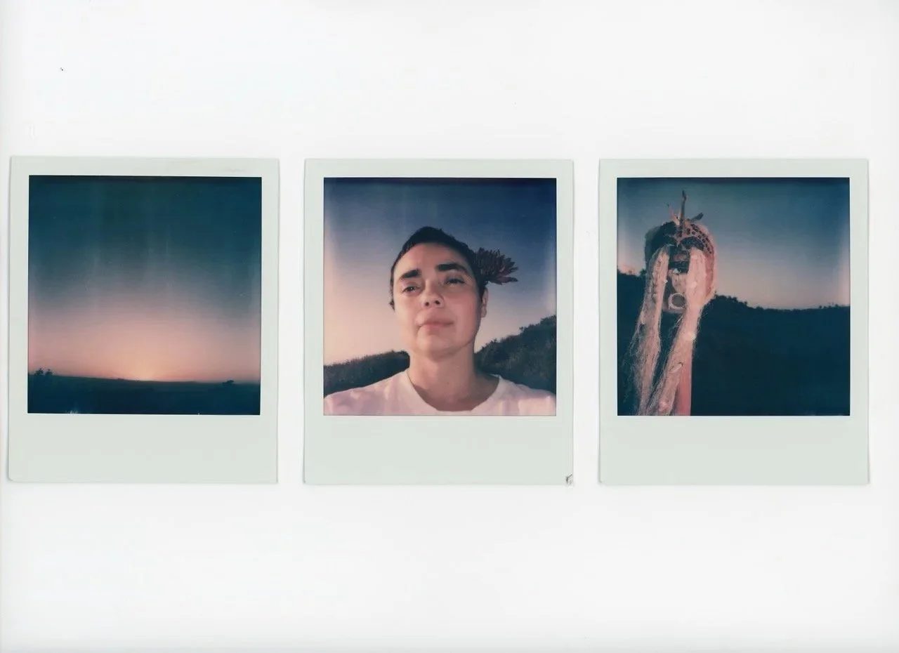 Three instant photographs on a white wall. The first shows a sunset with a gradient sky. The second features a woman with short dark hair, wearing a white shirt, outdoors during dusk. The third depicts a person with long hair covering their face with their hands, outdoors at sunset.
