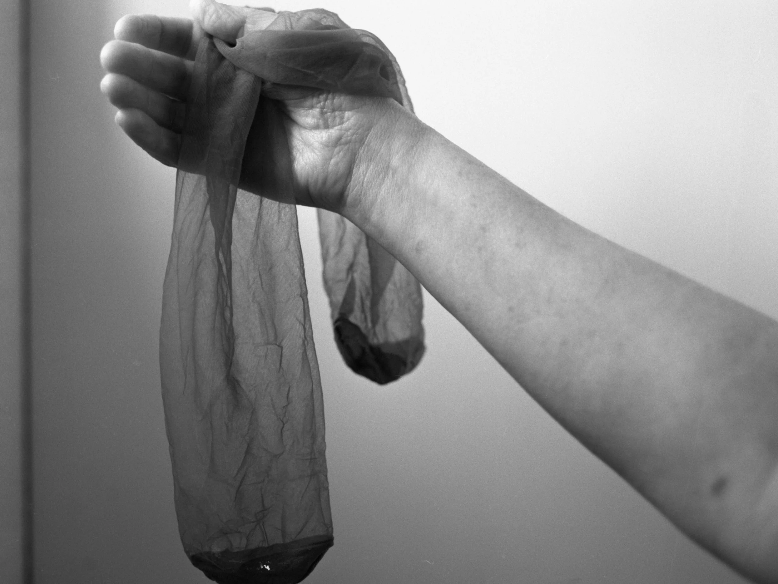 A black and white photo of a hand holding a crumpled piece of fabric or material against a plain background.