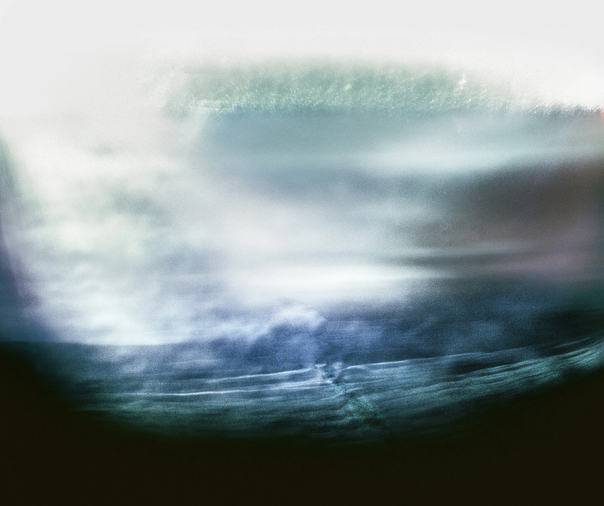 A photograph of water with waves and a cloudy sky reflected on the surface, creating a serene seascape scene.