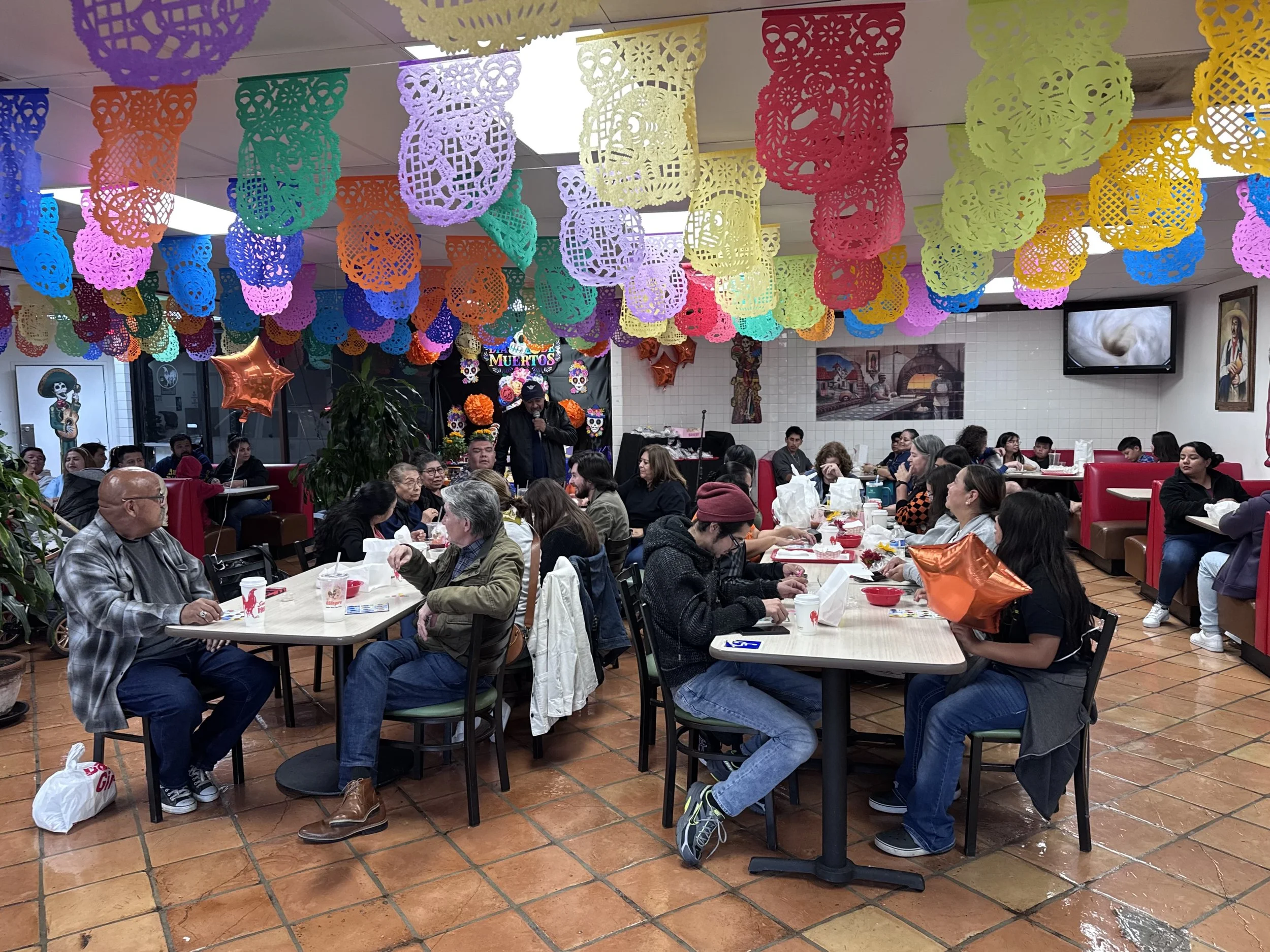 Packed El Gallo Giro dining room under papel picado during Lotería Night