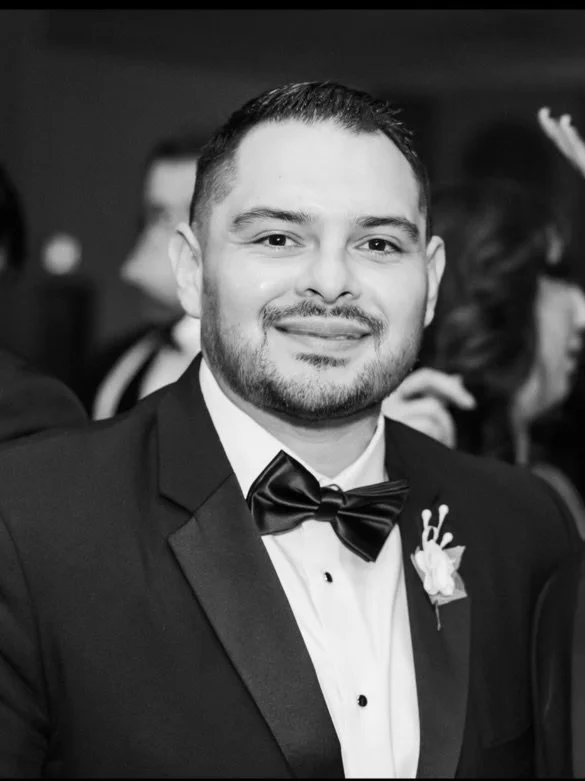 Man in tuxedo with bow tie and boutonniere smiling at formal event