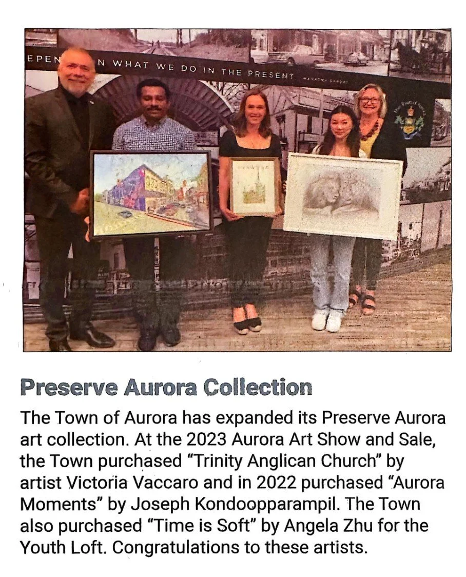 Group of five people holding artwork at an art event in Aurora, with a backdrop that says "What We Do in the Present" and displays historical images of the town.