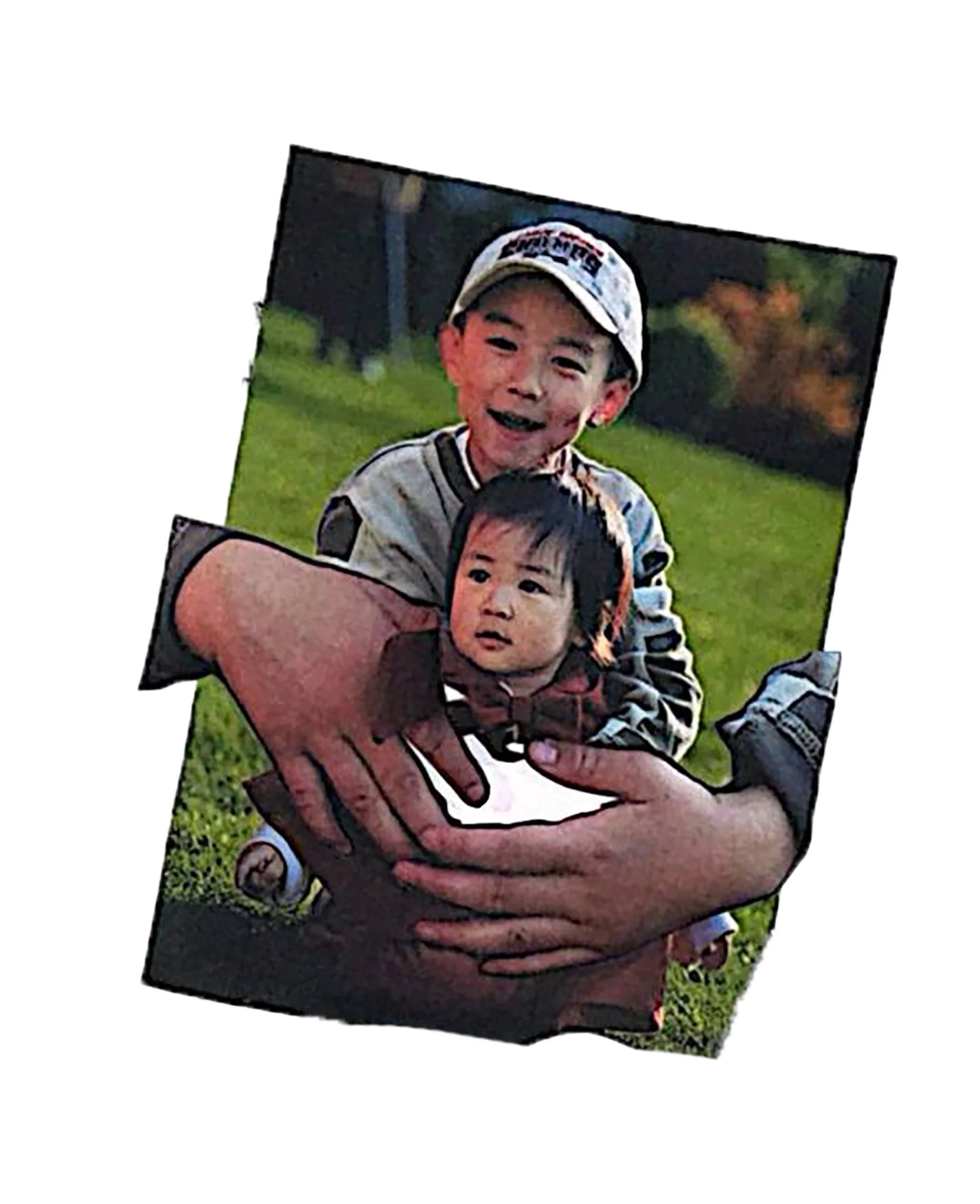 A person holding a young child with a green grassy background.
