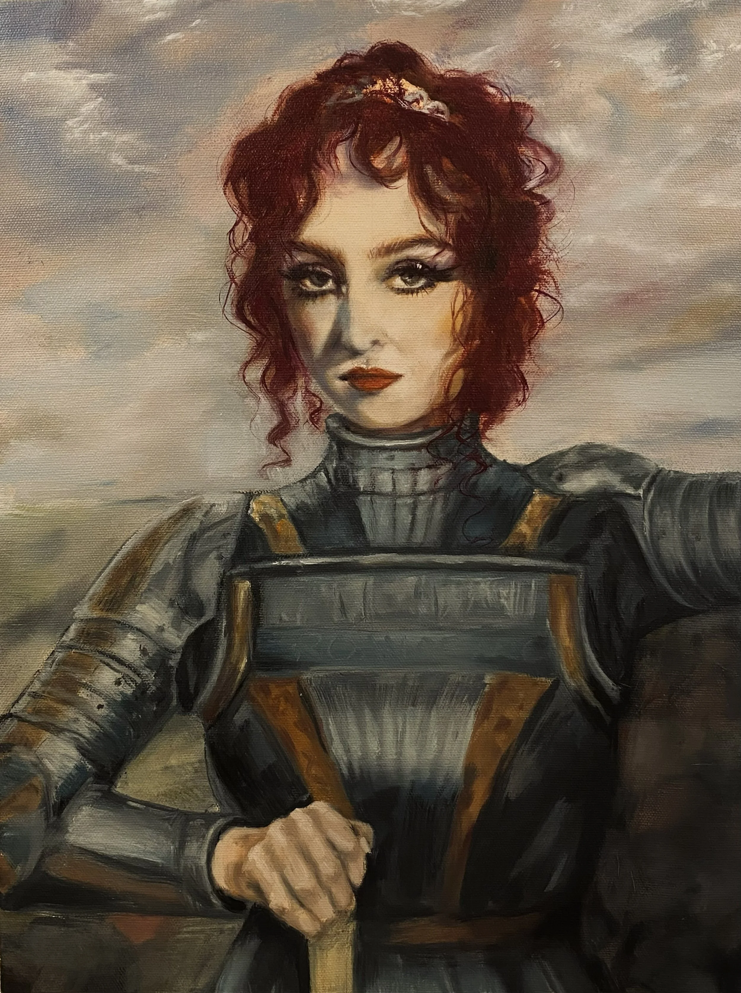 A woman in armor with curly red hair, standing against a cloudy sky, with a confident expression and clenched fist.