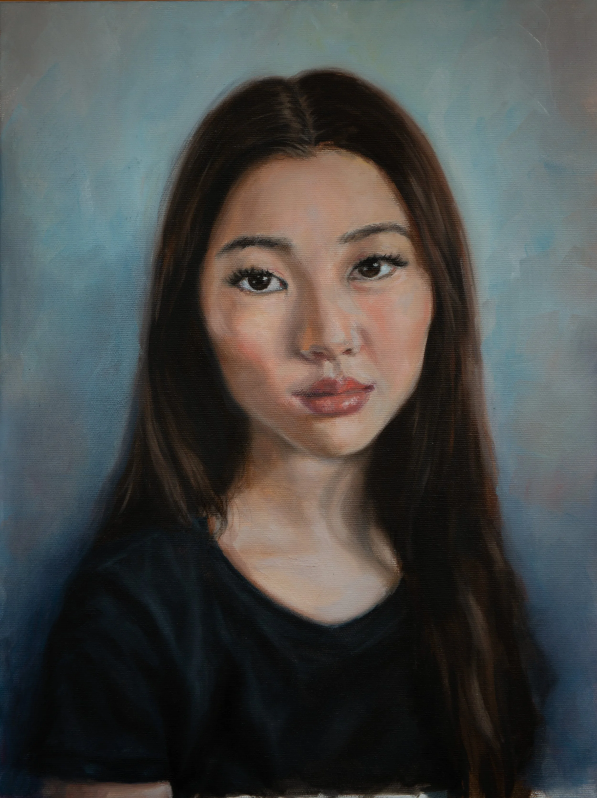 Self portrait with long brown hair, wearing a black top, against a blue background.