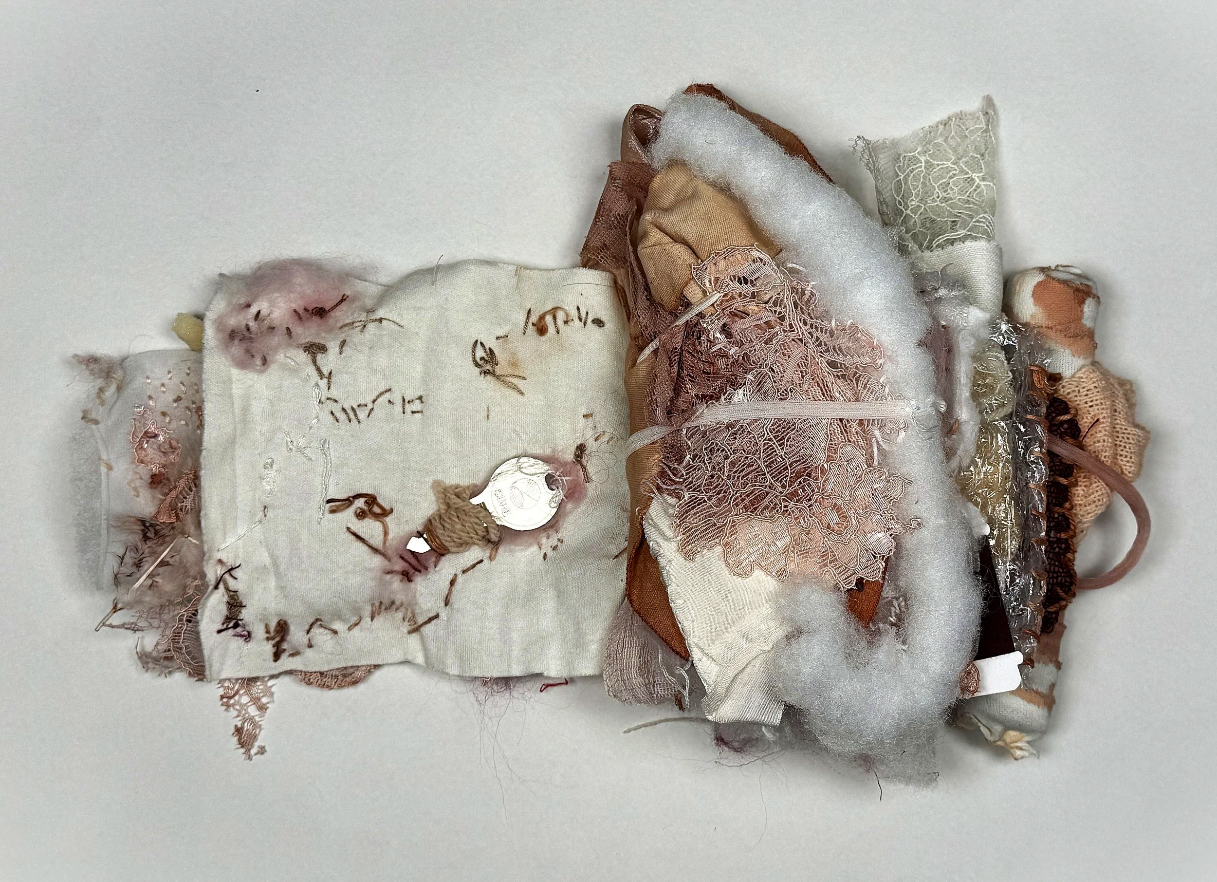 A collection of fabric scraps, lace, and textile materials in various neutral tones, arranged on a white surface.
