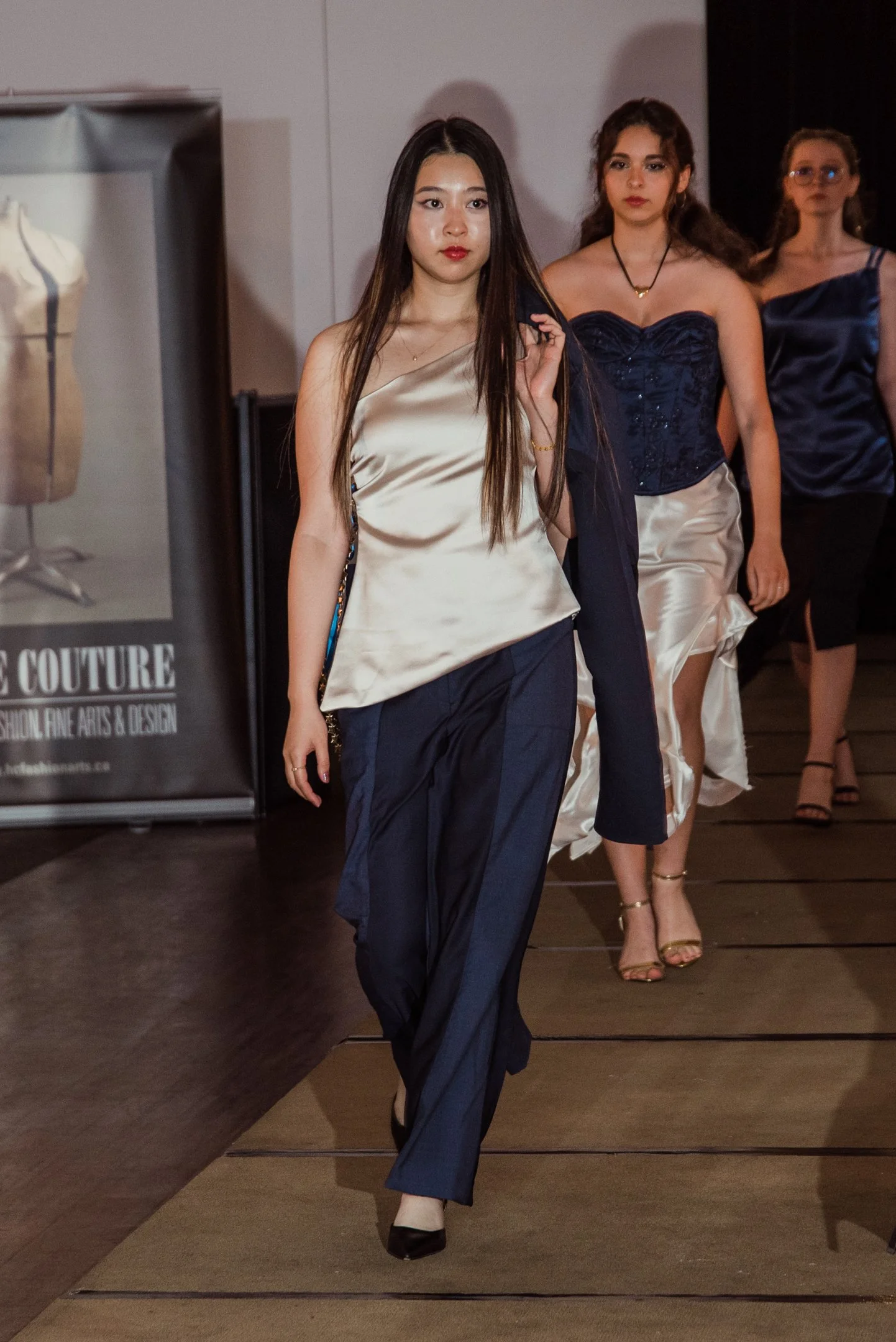 Fashion models walking on runway at a fashion event, dressed in elegant satin and silk garments.