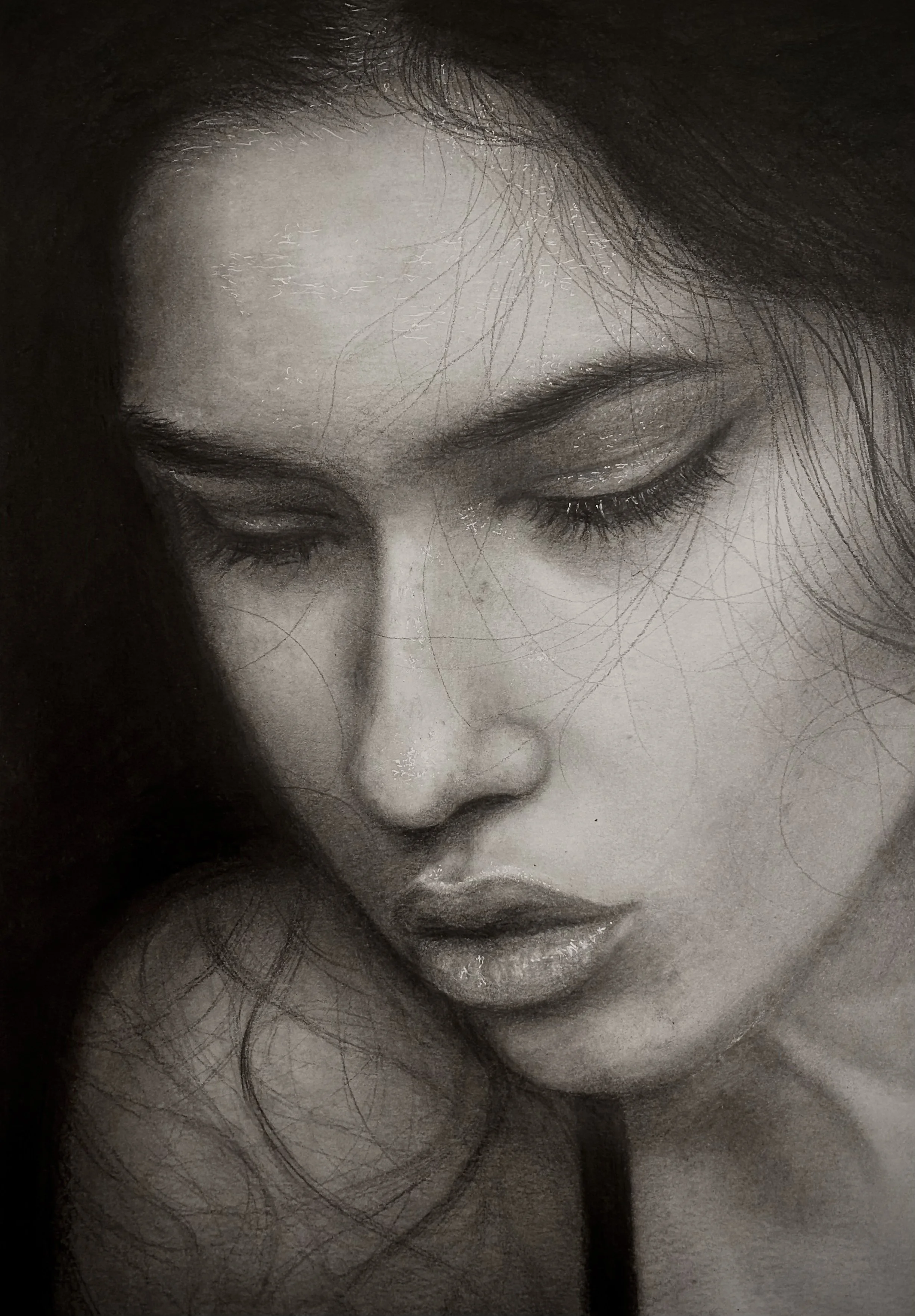 A close-up black and white photo of a woman with her eyes closed, showing her face and some dark hair. She appears to be calm or in thought.