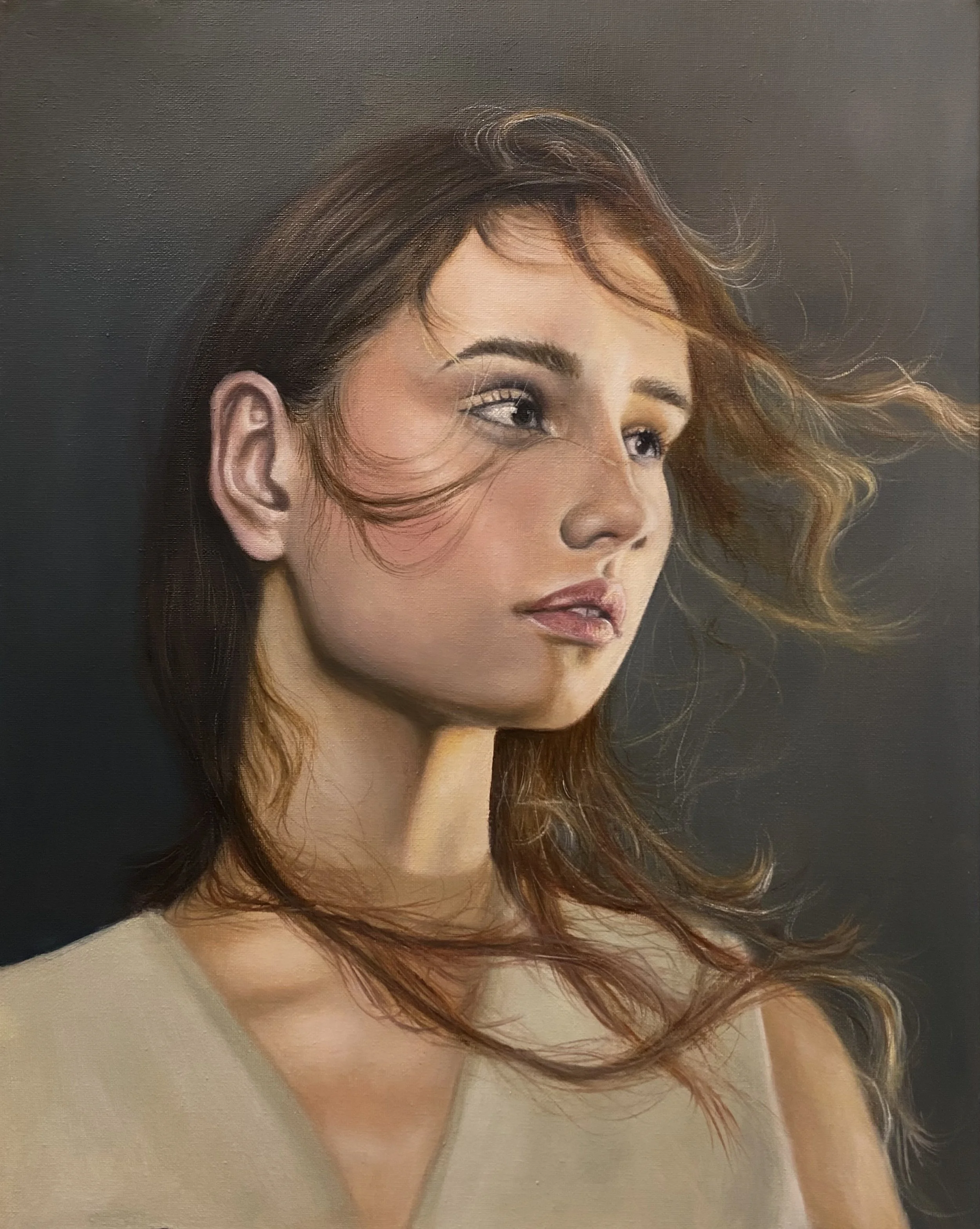 A close-up portrait of a woman with wavy, auburn hair flowing, against a dark background.