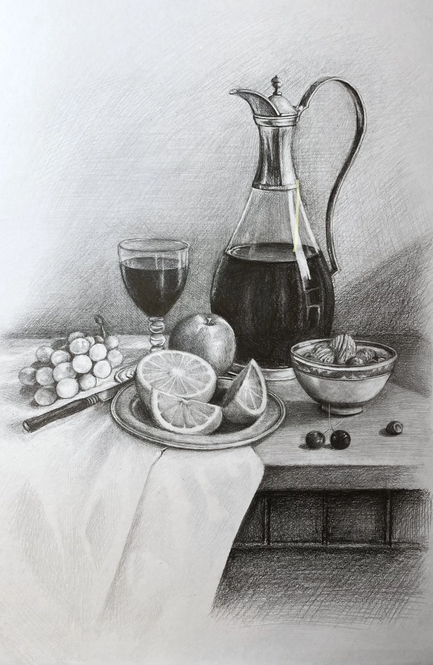 A detailed black and white still life drawing of a table with a carafe of dark liquid, a glass of wine, an apple, orange slices, grapes, cherries, and a bowl of nuts. A small rounded vase is in the foreground, and the table is partly covered with a cloth.