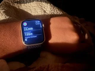 Close-up of a smartwatch on a person's wrist displaying steps taken, distance traveled, and activity minutes.