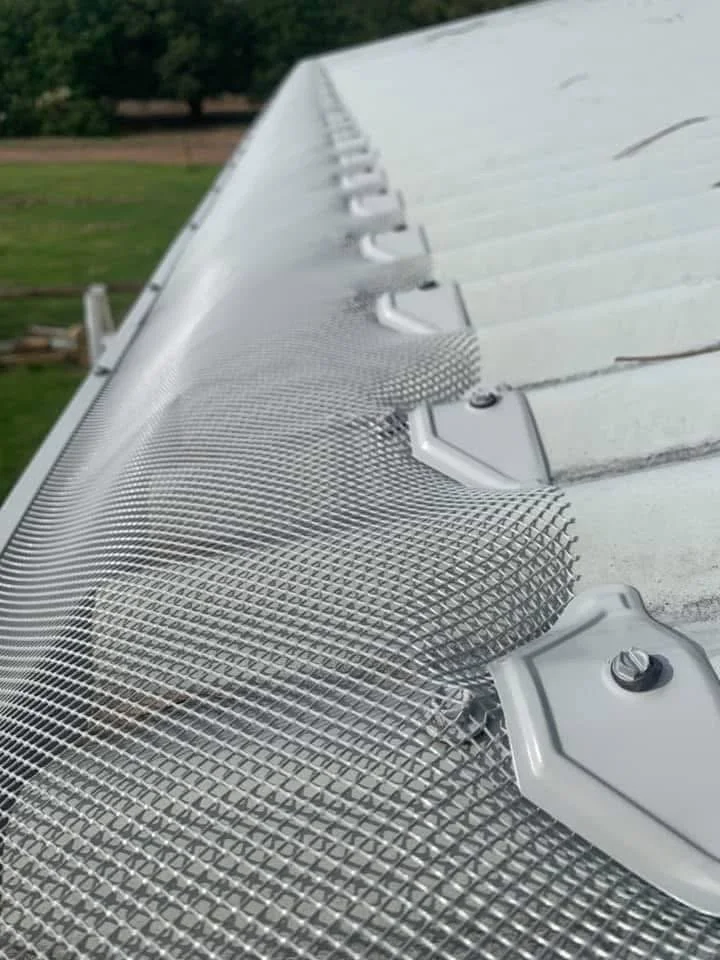 Close-up of security camera on a building roof with protective mesh.