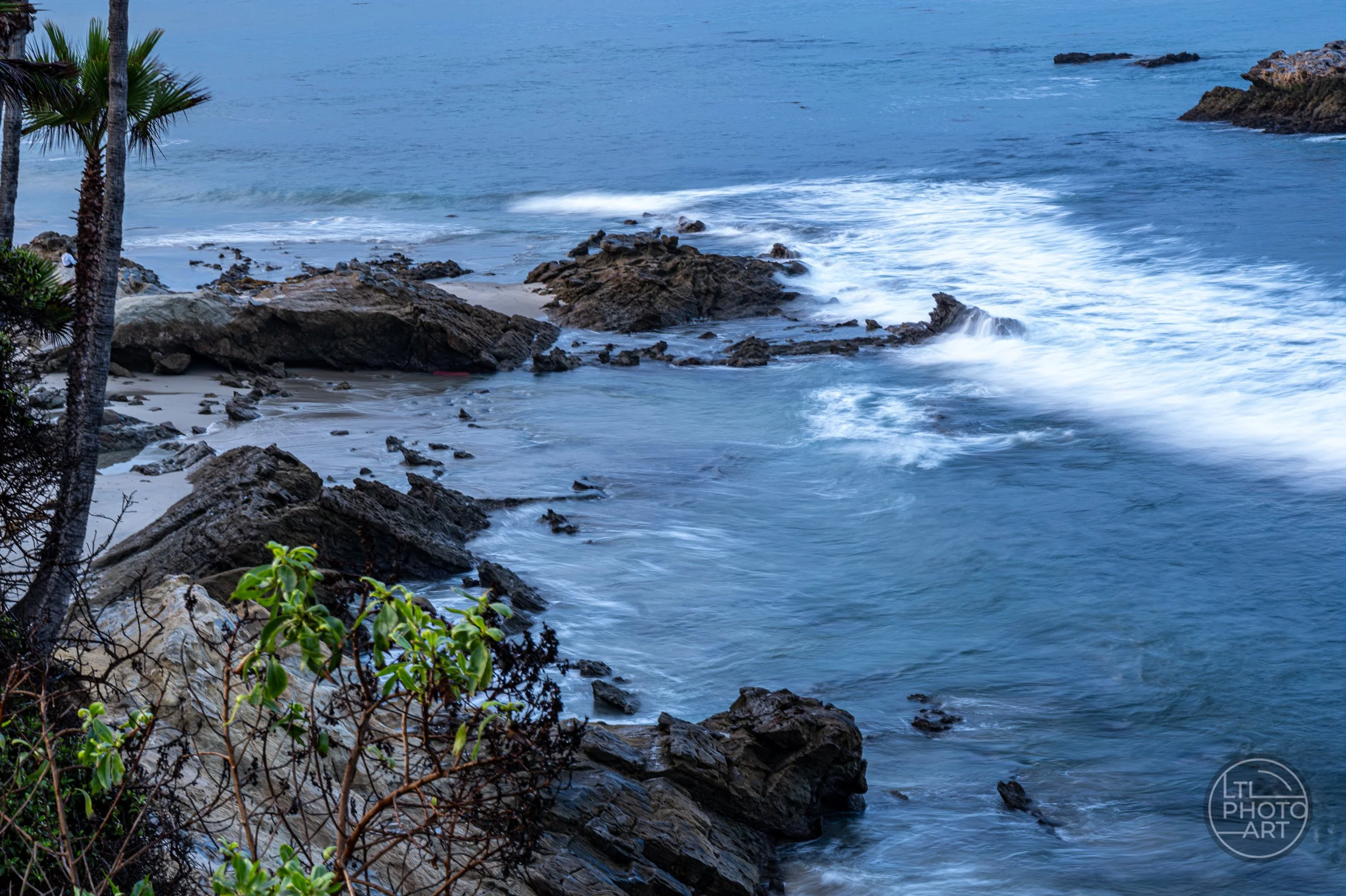 Long-exposure waves flowing around coastal rocks at the south end of Rockpile Beach, viewed from Heisler Park in Laguna Beach, California.
