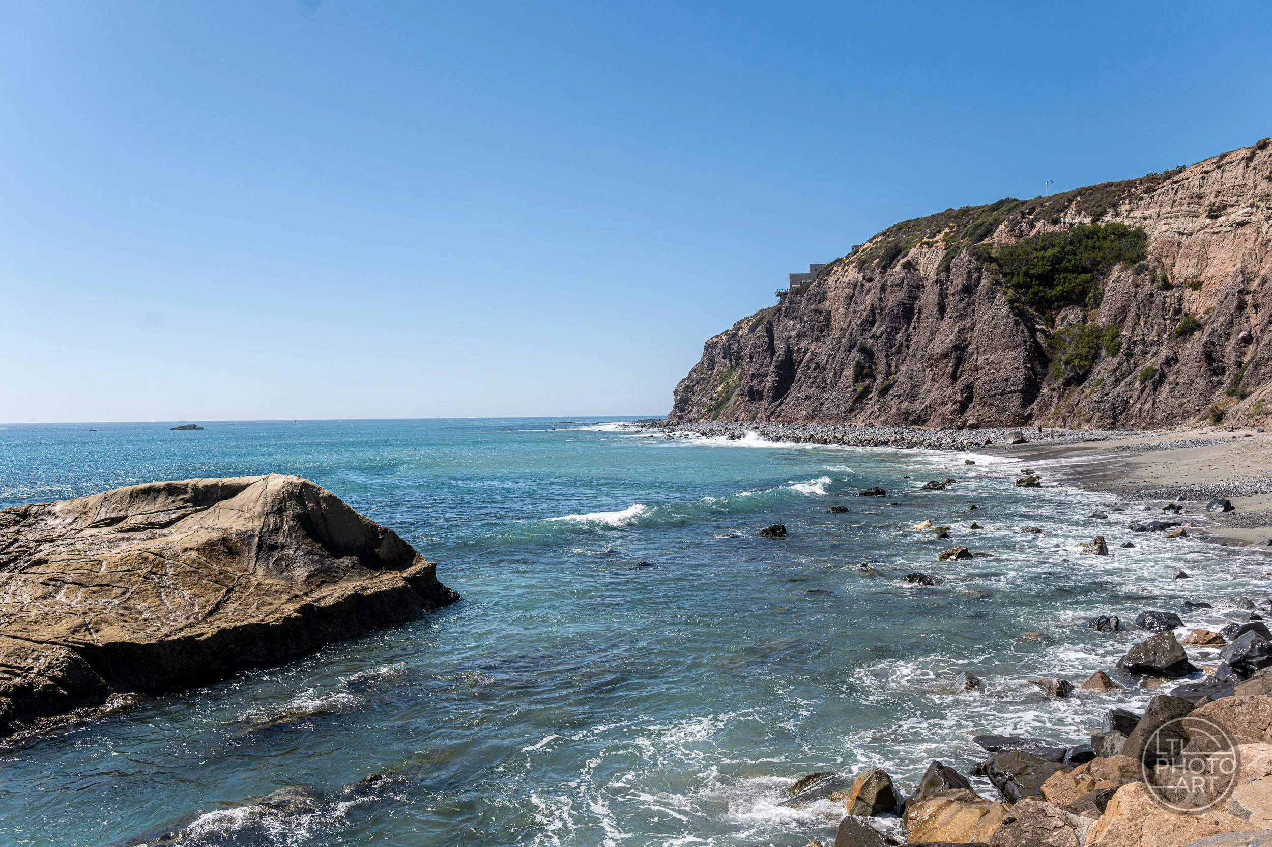 Rocky coastline and blue Pacific water outside Dana Point Harbor, looking north toward The Strand in Dana Point, California.