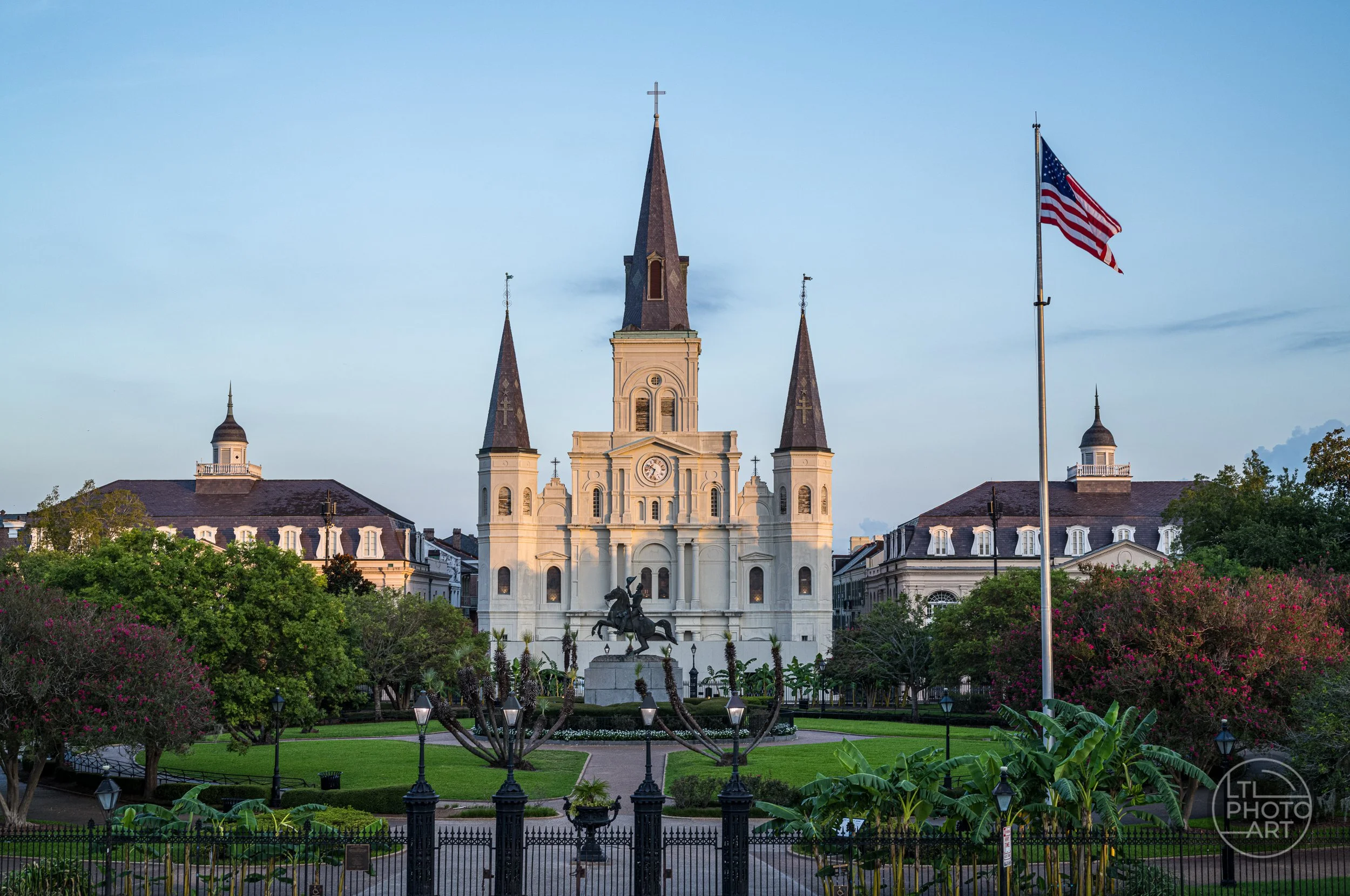 St. Louis Cathedral viewed from Jackson Square in New Orleans, with the Andrew Jackson statue, American flag, gardens, and morning light.