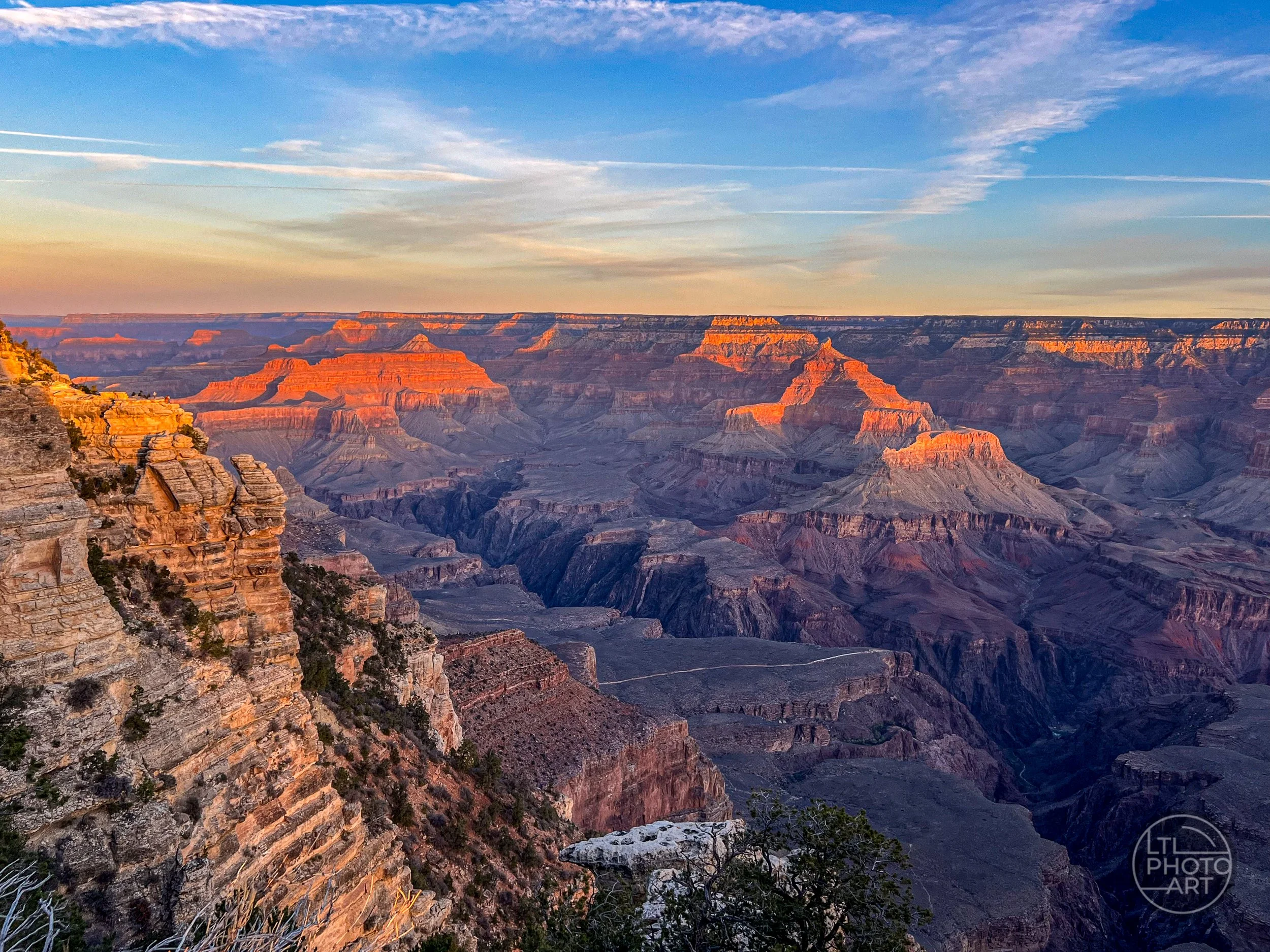Sunset light glowing across layered rock formations and deep canyons viewed from the South Rim of Grand Canyon National Park, Arizona.