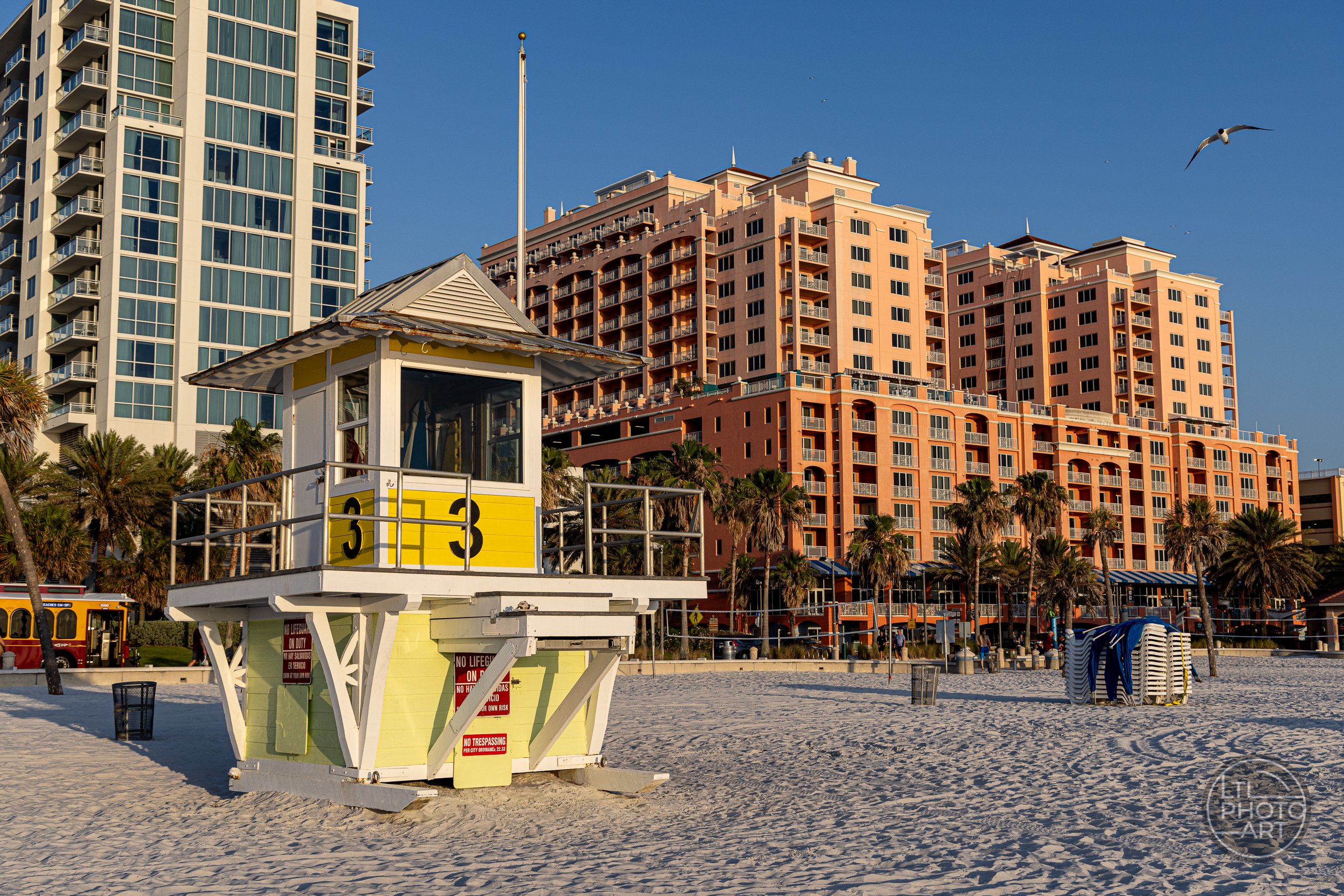 Lifeguard Tower 3 on Clearwater Beach, Florida, with palm trees and beachfront hotels rising in the background.