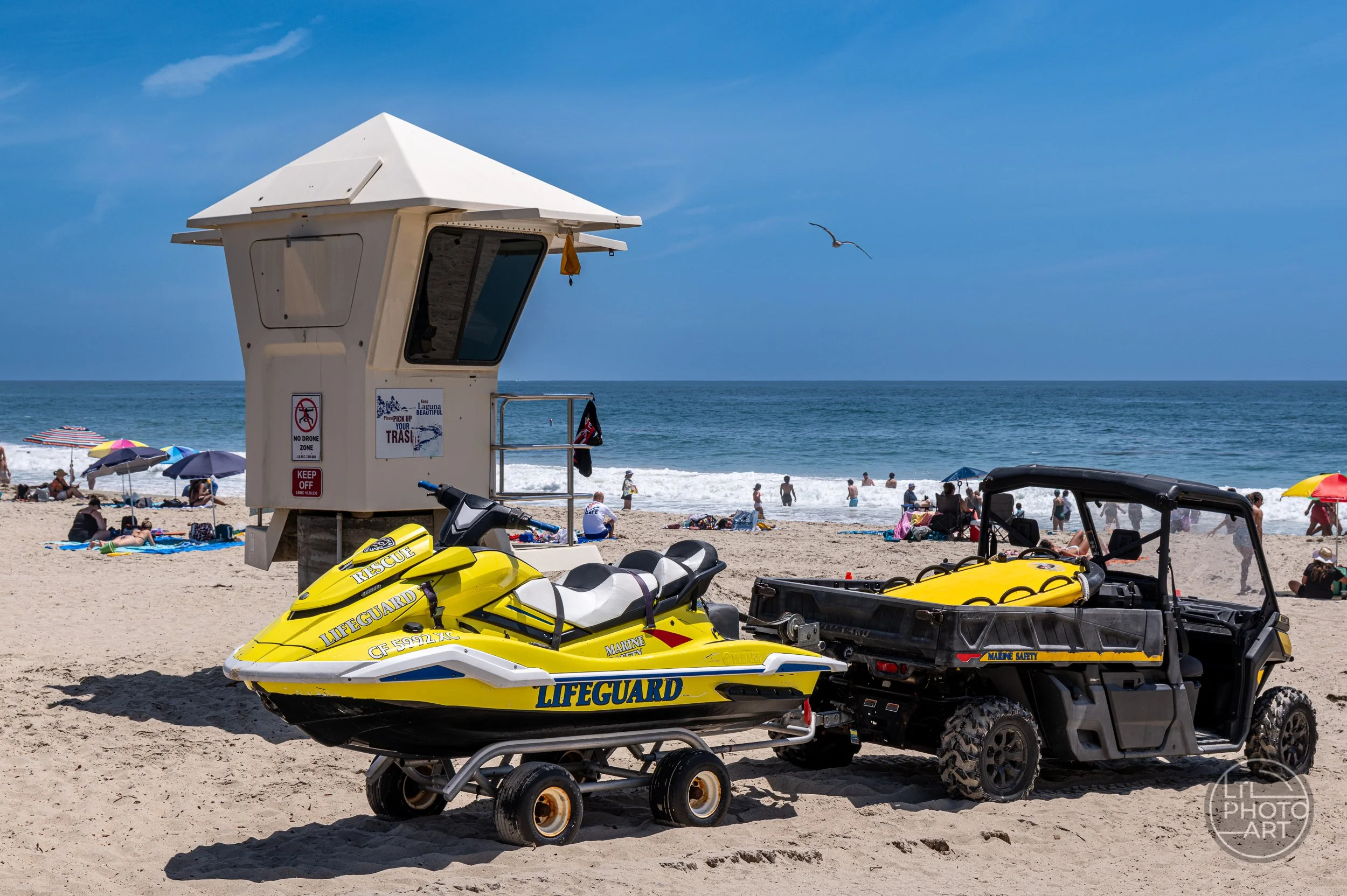 Lifeguard tower with a yellow rescue watercraft and marine-safety vehicle on Main Beach in Laguna Beach, California.