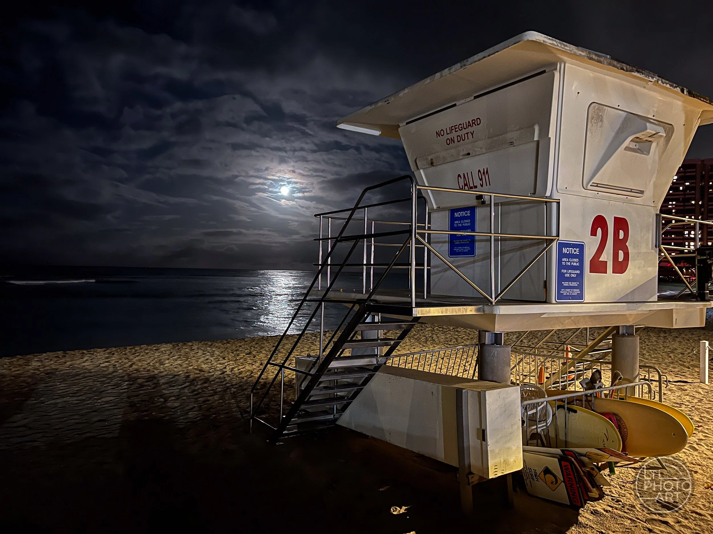 Lifeguard Tower 2B on Waikiki Beach, Oahu, Hawaii, in the early morning with a full moon and its reflection on the ocean.