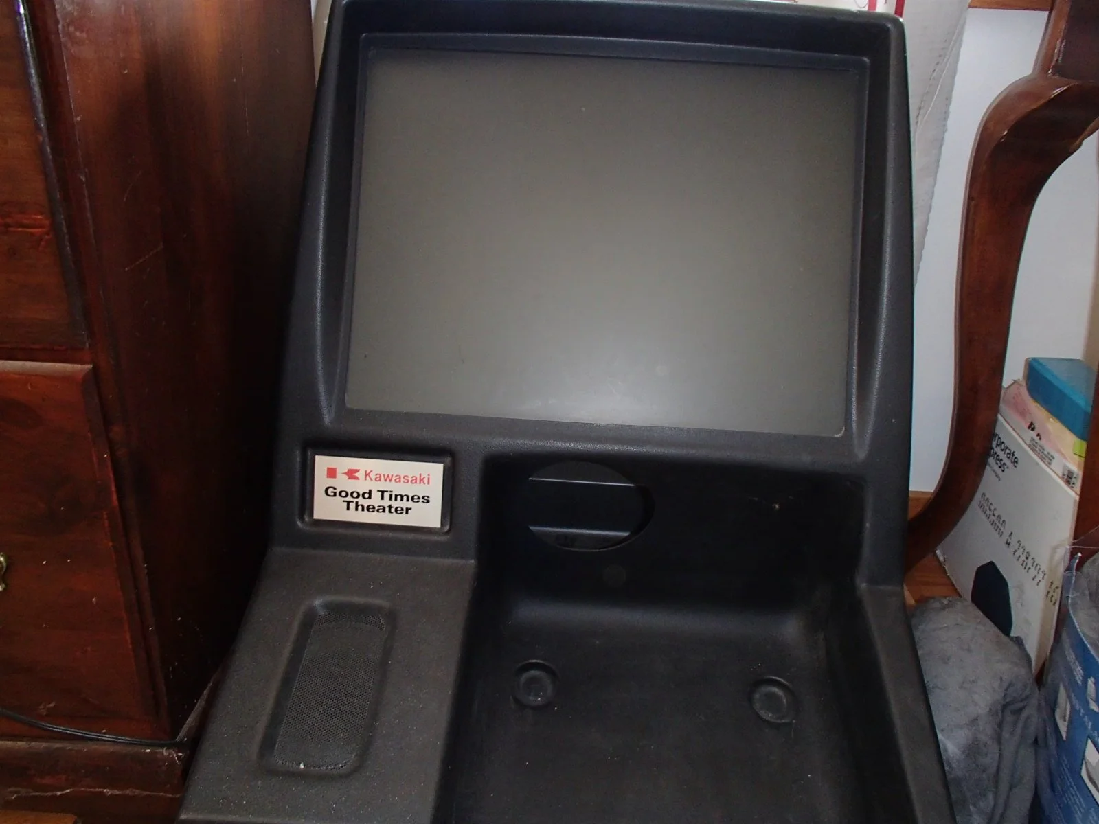 A vintage Kawasaki Good Times Theater arcade game machine with a large screen, no game controls, and a sticker on the lower left that says 'Kawasaki Good Times Theater.'