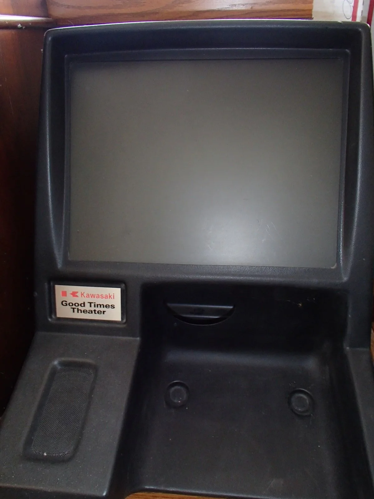 Arcade gaming machine with a blank screen, a speaker on the left, and a sticker that says 'Kawasaki Good Times Theater'.