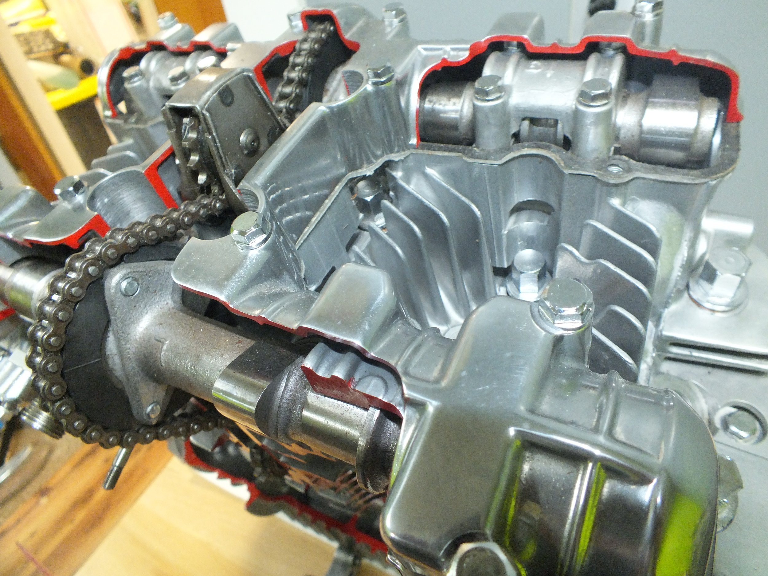 Close-up view of a metallic engine part with a timing chain and engine components inside a machinery or vehicle.