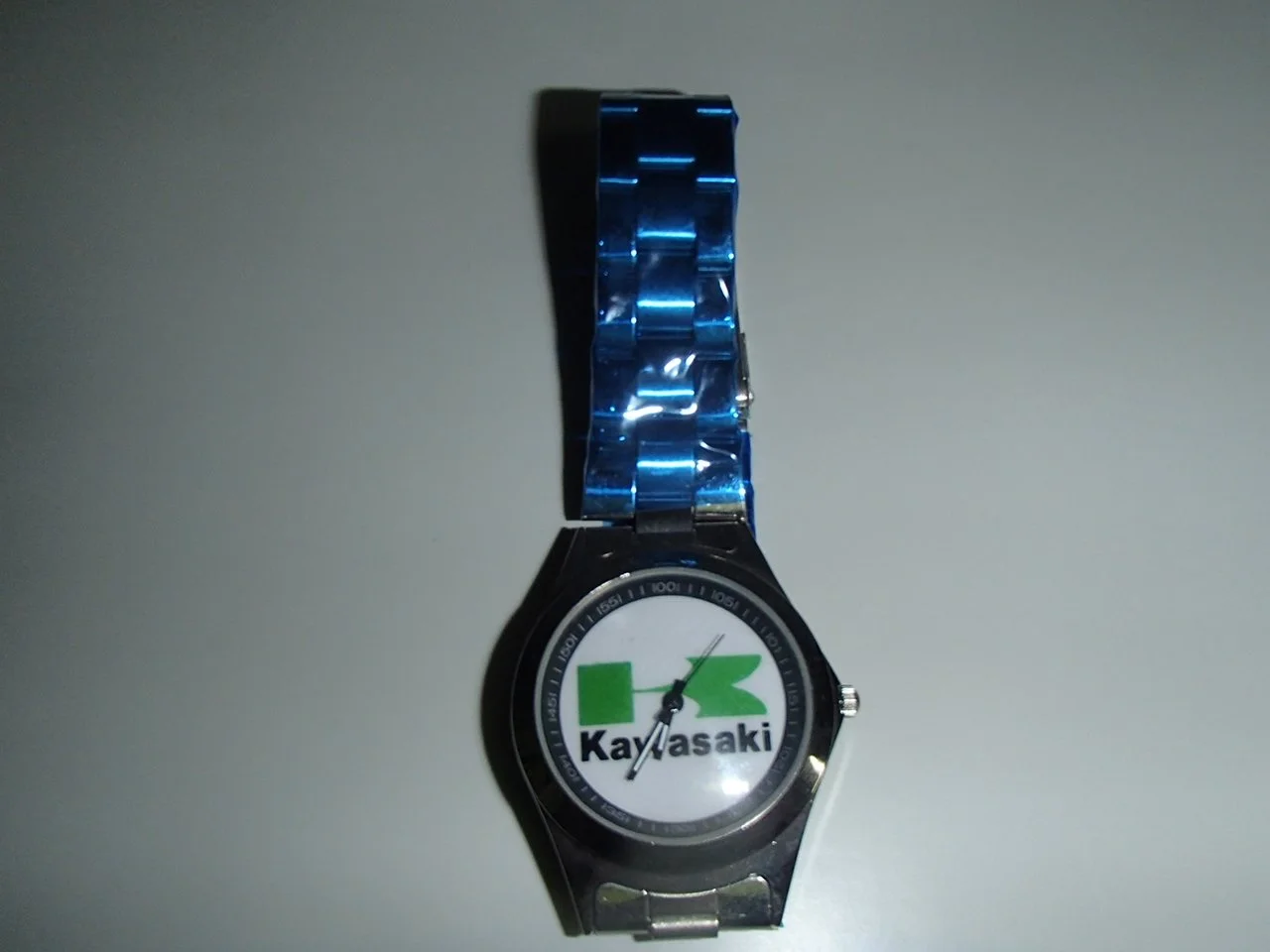 A wristwatch with a Kawasaki logo on the dial, featuring green and black elements, and a metal band.