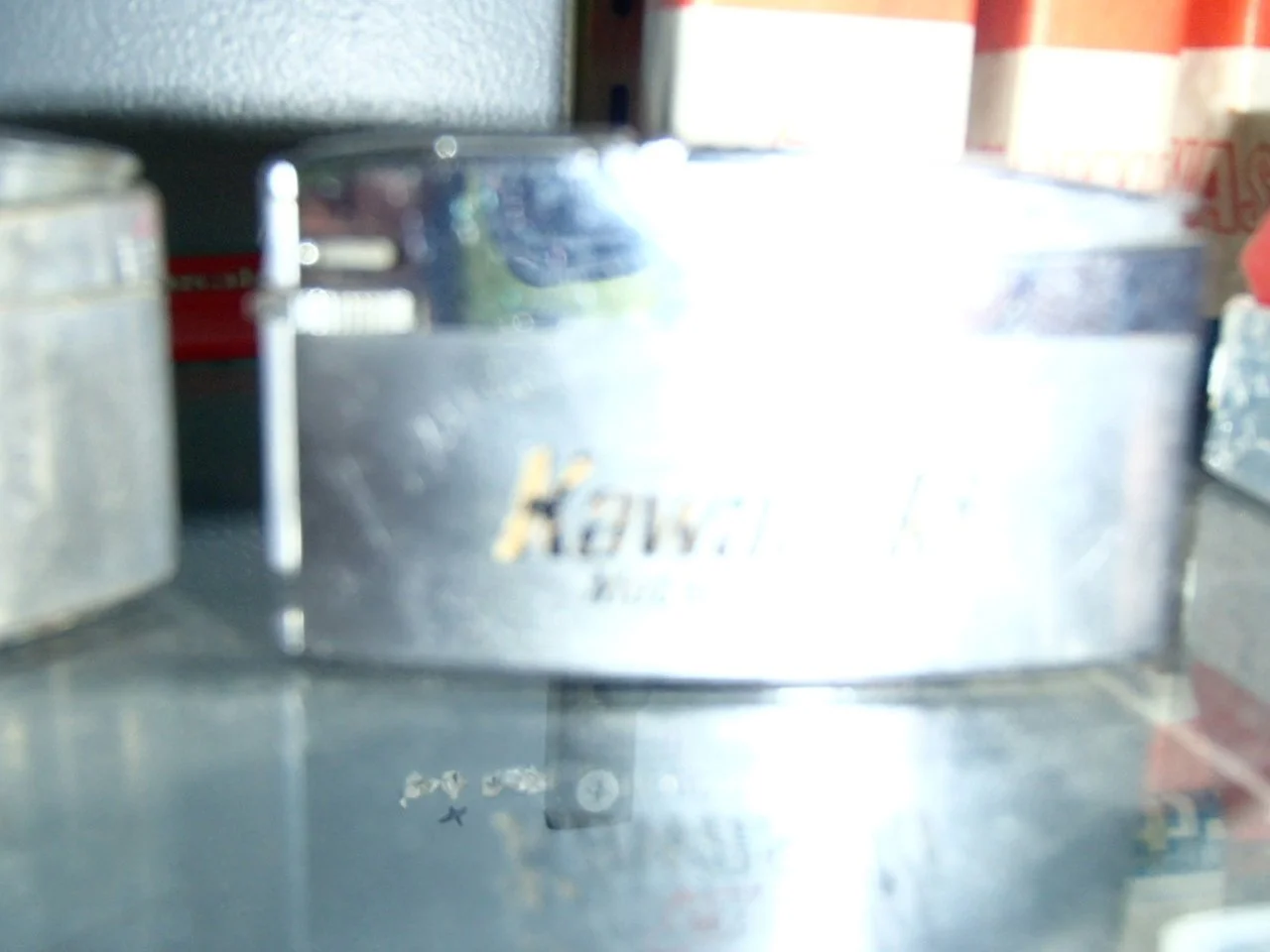 Close-up view of a metallic object with the brand name 'Katsugi' engraved on it, surrounded by shelves with other items in the background.
