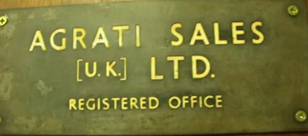 Metal sign reading 'AGRATI SALES [U.K.] LTD. REGISTERED OFFICE' in yellow letters on a dark background.