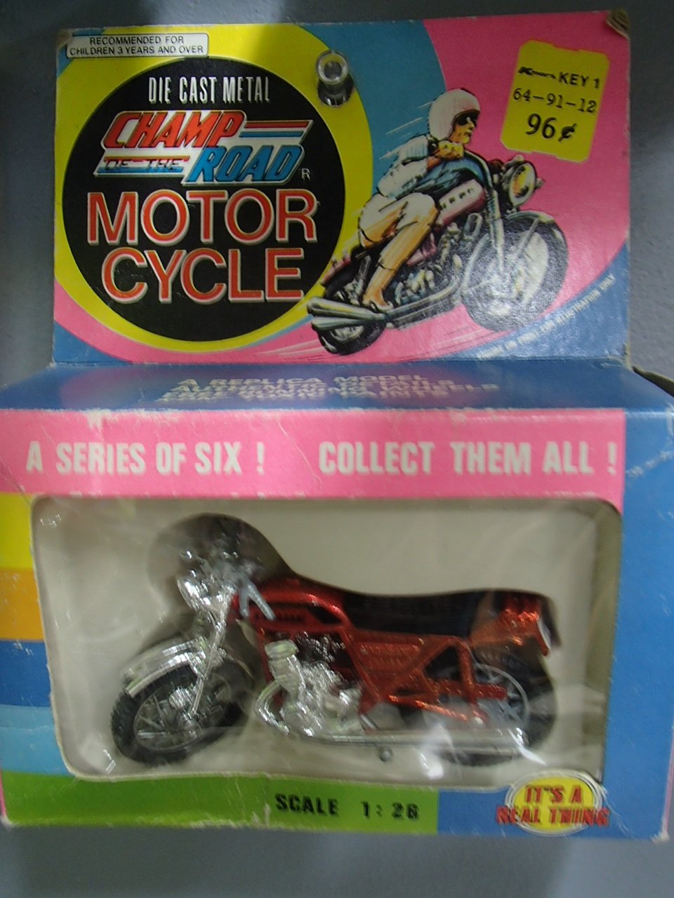 A toy motorcycle in its original packaging, labeled as part of the 'Champ the Road' series, with a colorful design and illustration of a rider on a motorcycle on the box.