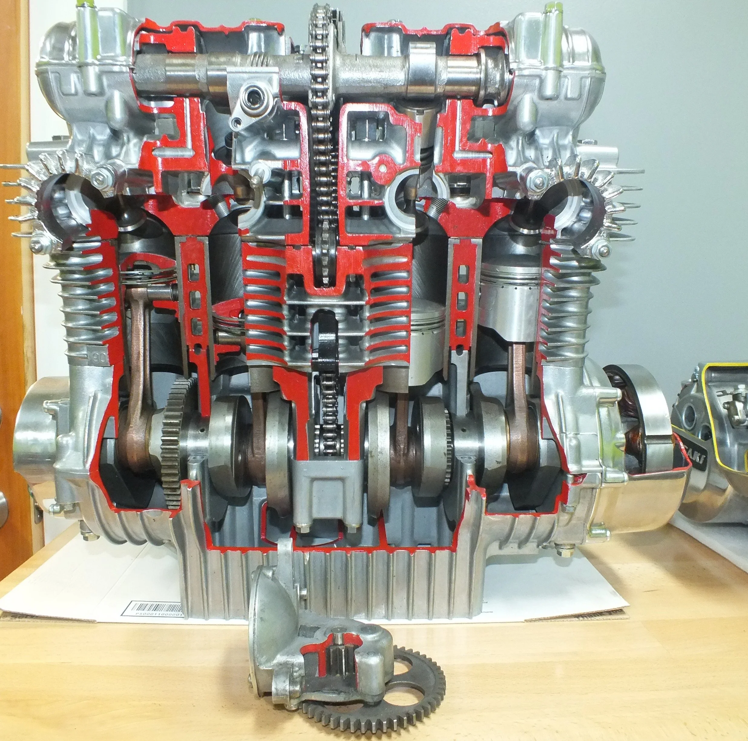 Cutaway view of an internal combustion engine showing cylinders, pistons, crankshaft, timing chain, and internal components.