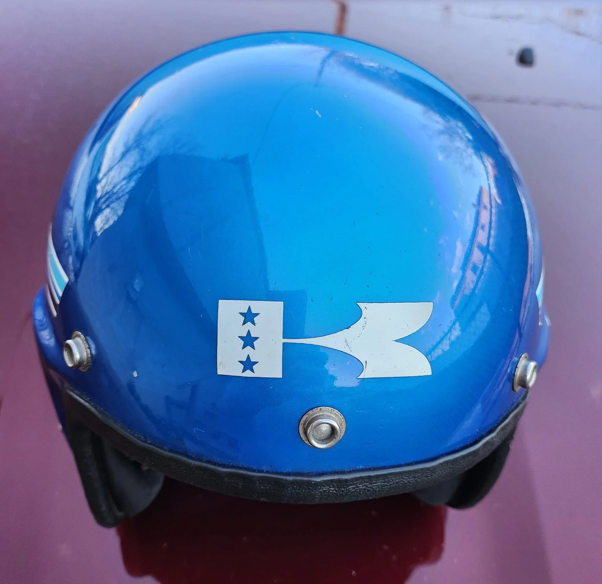 Close-up of a blue paint sample container with a white label featuring a star, placed on a dark surface.