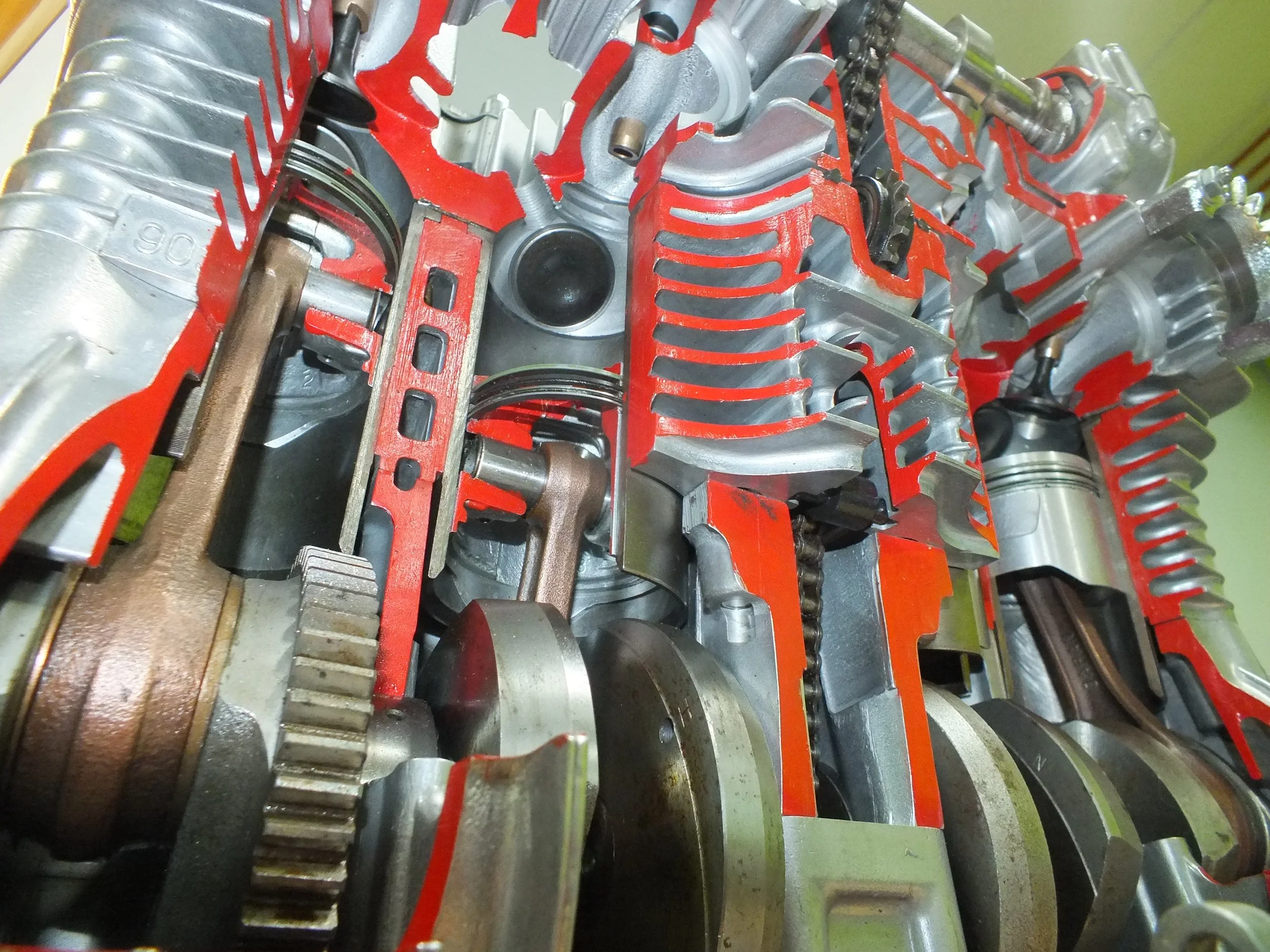 Close-up of an engine block, showing various metal components including gears, pistons, and red-painted parts inside.