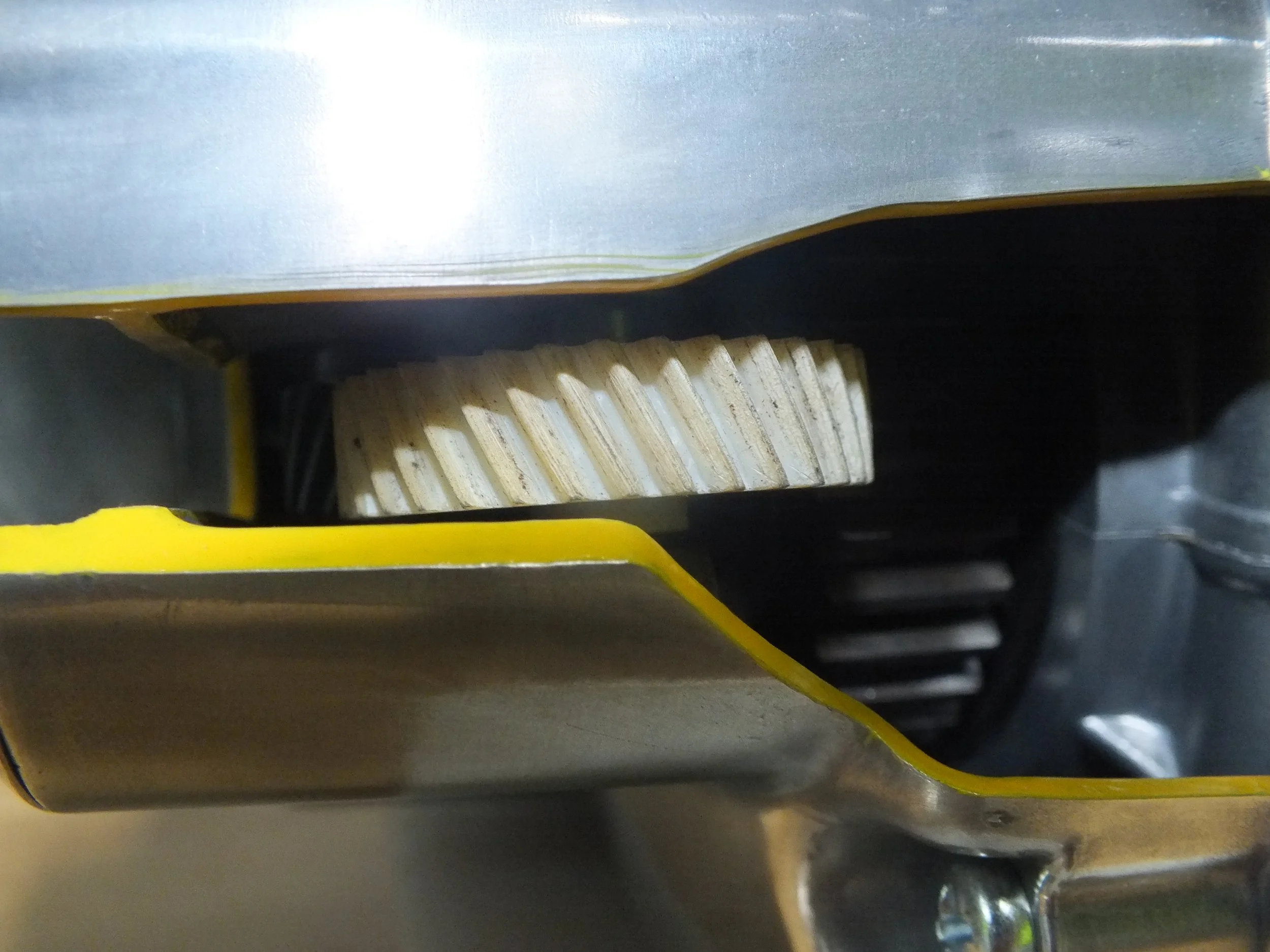 Close-up of a metal gear or machine part with layered yellow and gray components.
