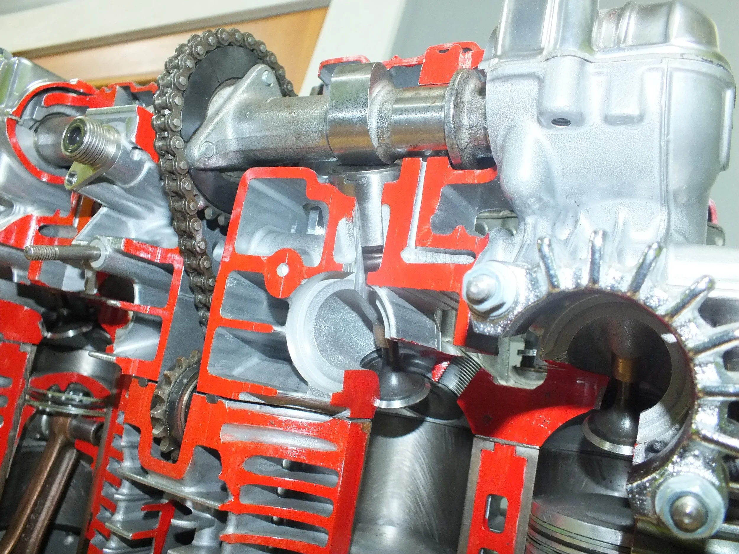 Close-up of an engine block with visible timing chain and internal components, held in a red engine stand.