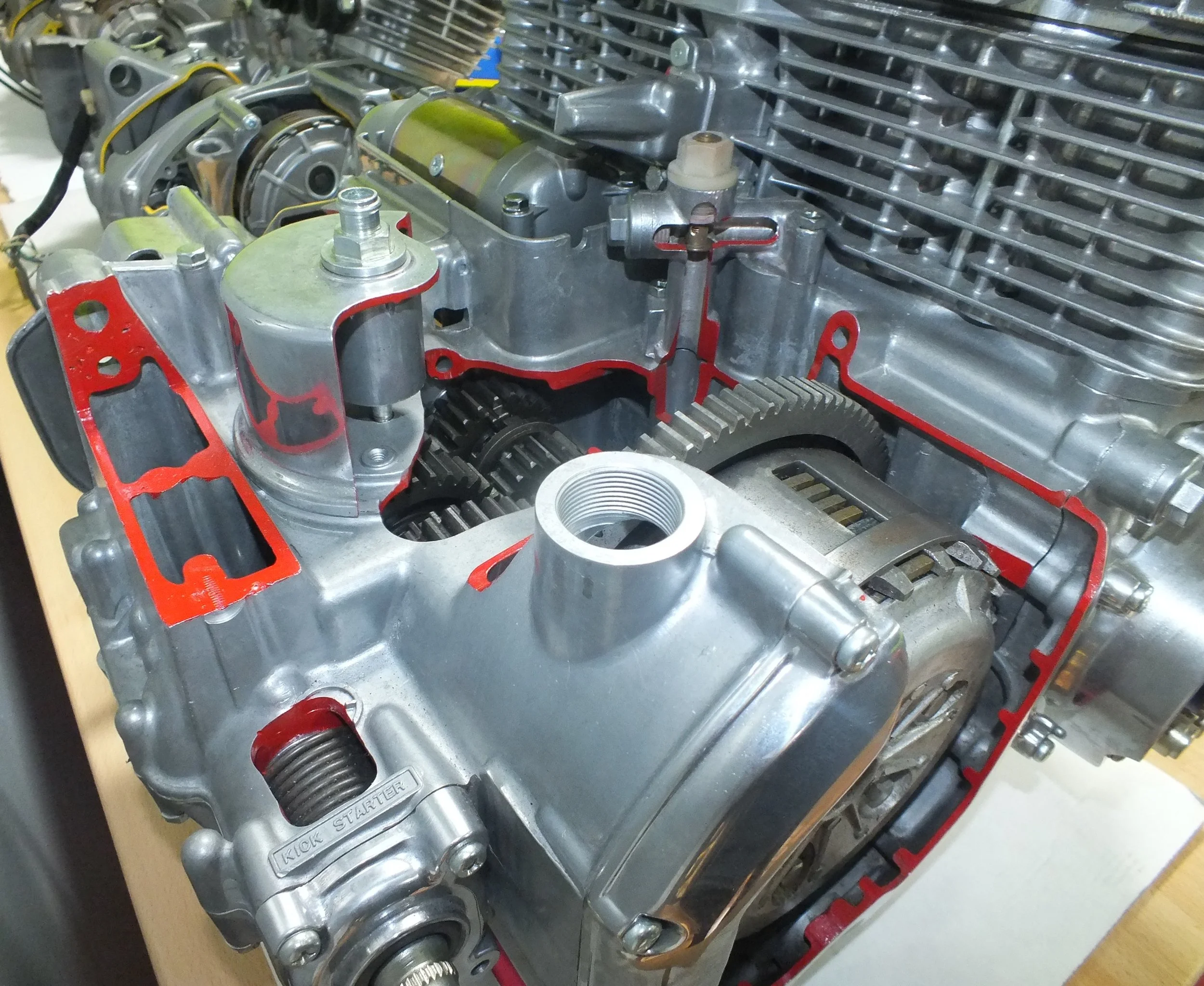 Close-up view of a partially assembled engine with various metal components, gears, and red gaskets visible.