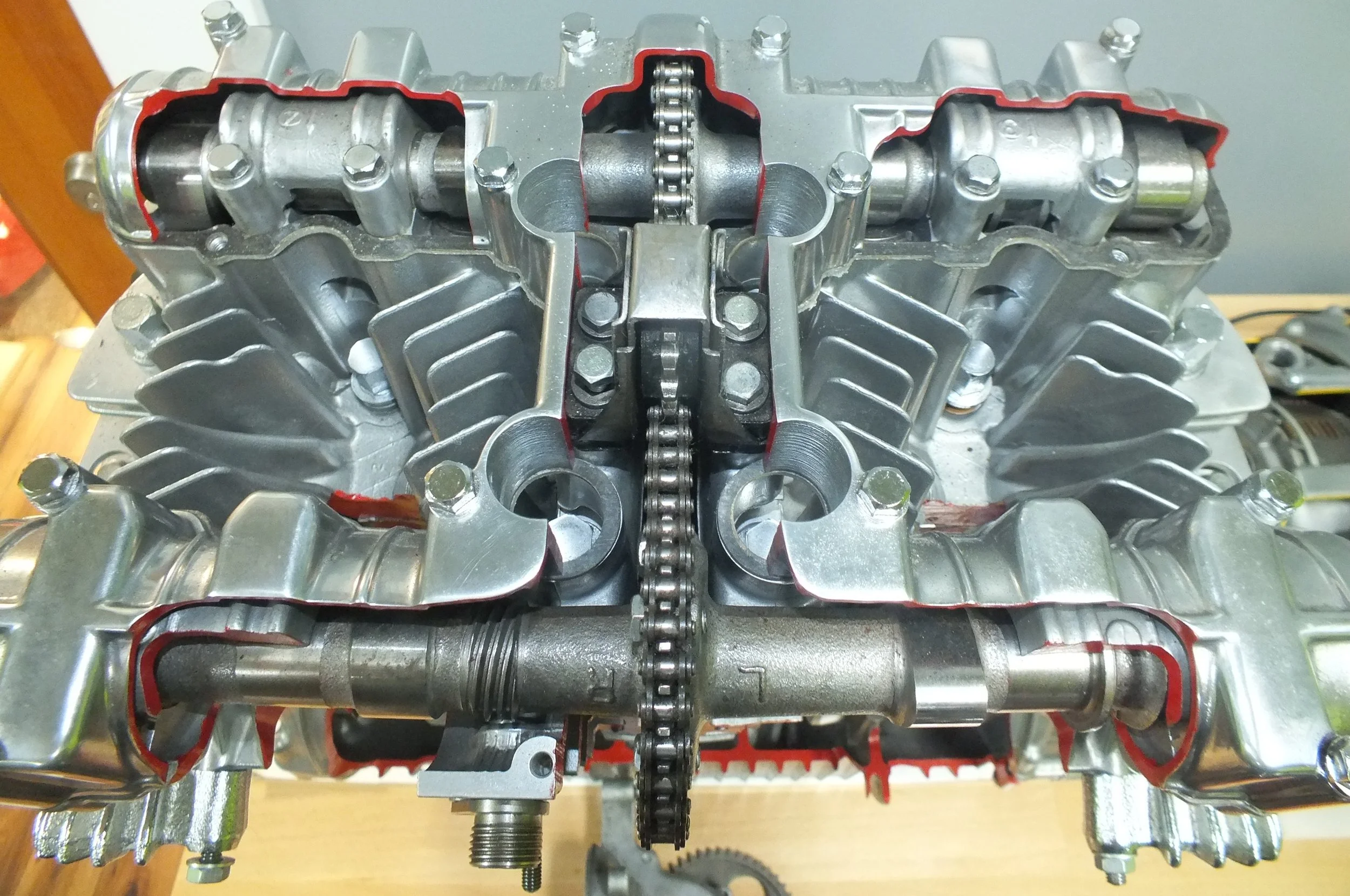Close-up of an internal view of a metallic engine component, showing a chain drive and various mechanical parts with red gaskets around the edges.