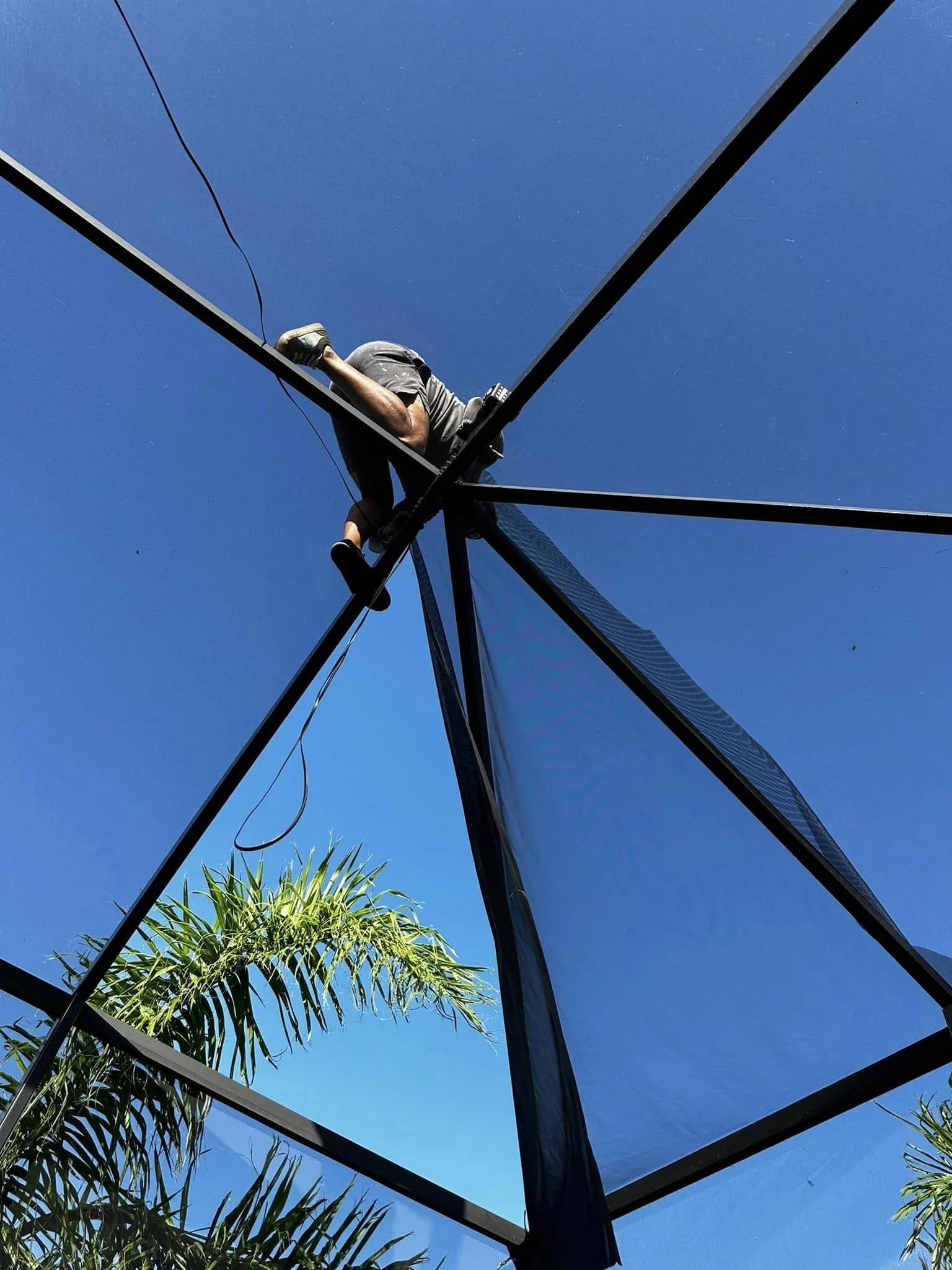 Daria’s Multiservices technician performing a pool cage roof screen repair, representing professional workmanship and warranty service.
