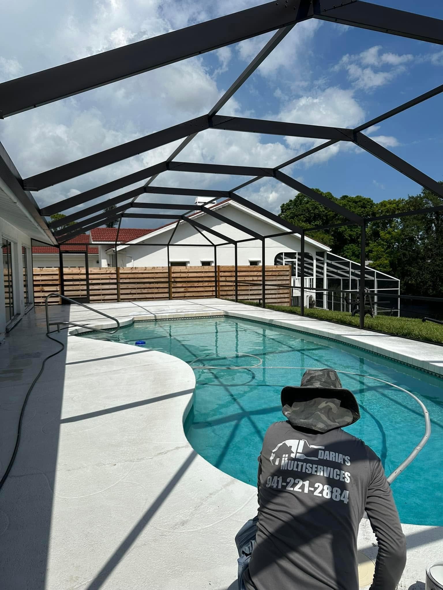 Daria’s Multiservices technician inspecting a residential pool cage and pool deck before restoration and maintenance work.