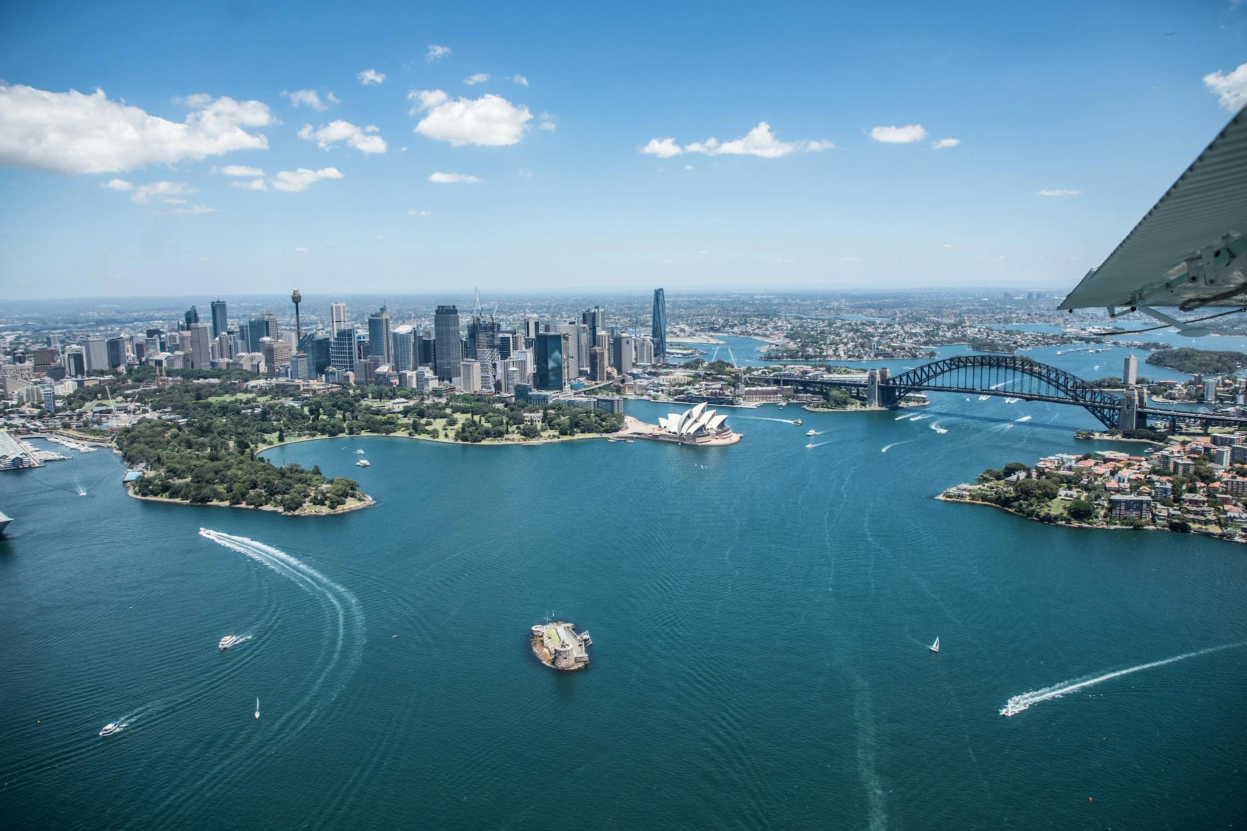 Aerial view of Sydney Harbour with the Sydney Opera House, Sydney Harbour Bridge, and downtown skyline, seen from a helicopter.