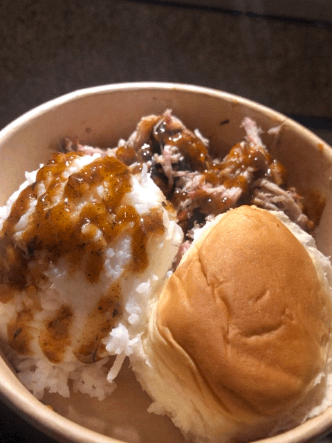 Bowl of rice with shredded beef, a dinner roll, and a soft-boiled egg topped with gravy.